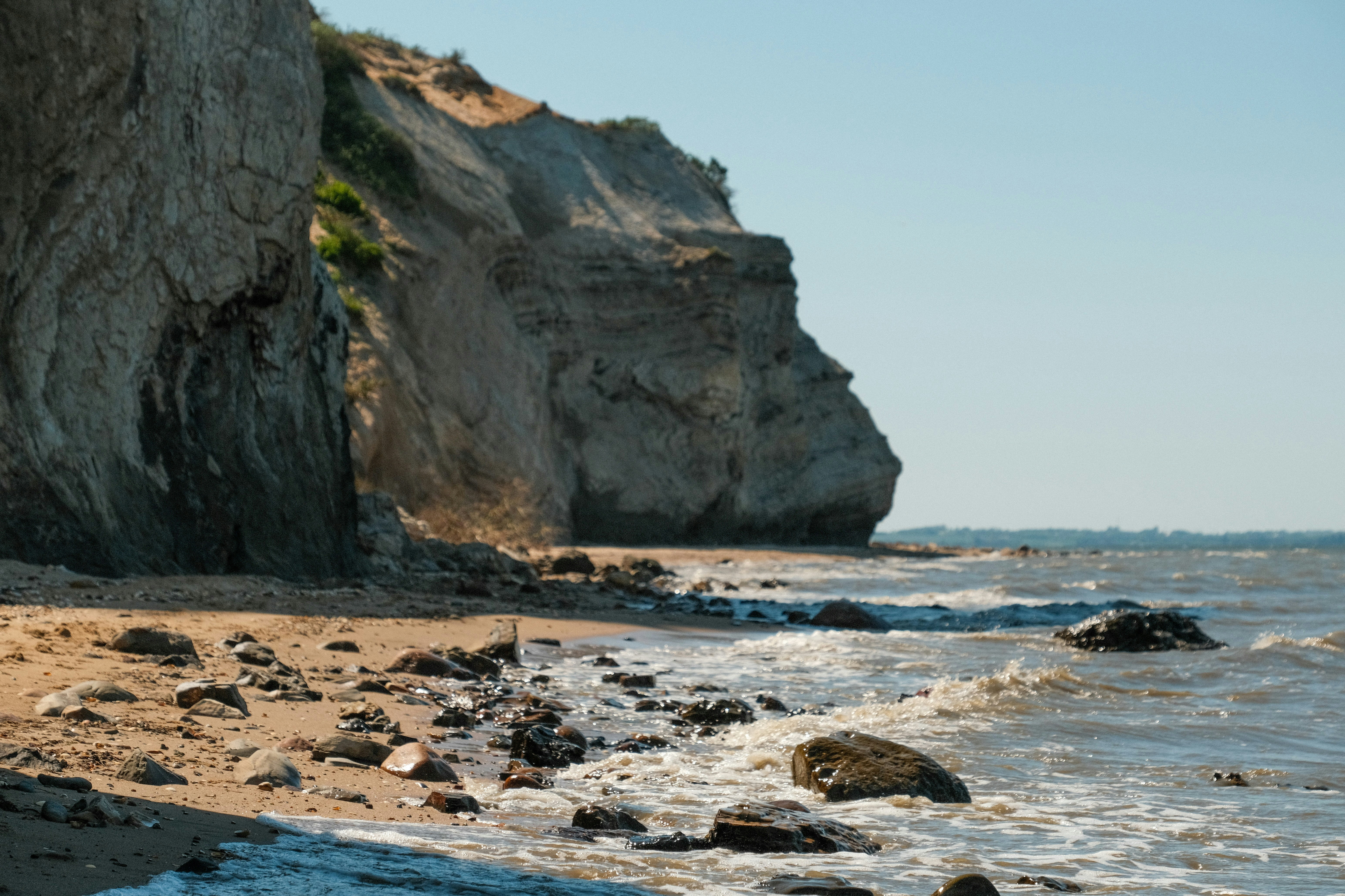 a beach with rocks and water next to a cliff