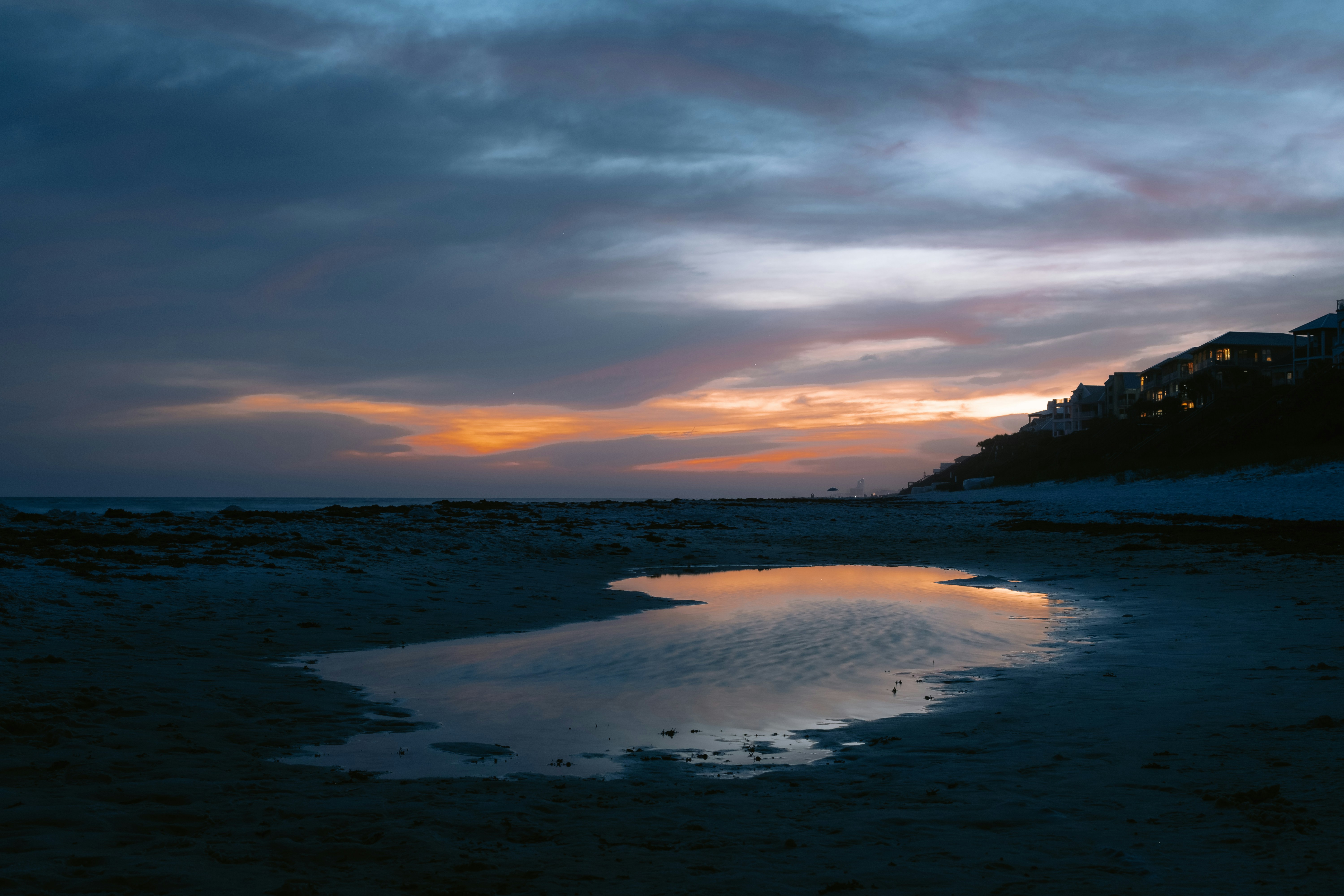 the sun is setting on the beach with a reflection in the water