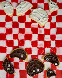 a checkered table cloth with cookies decorated like ghost faces