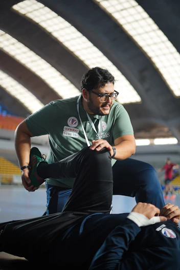 a man in a green shirt is doing something on another man's leg