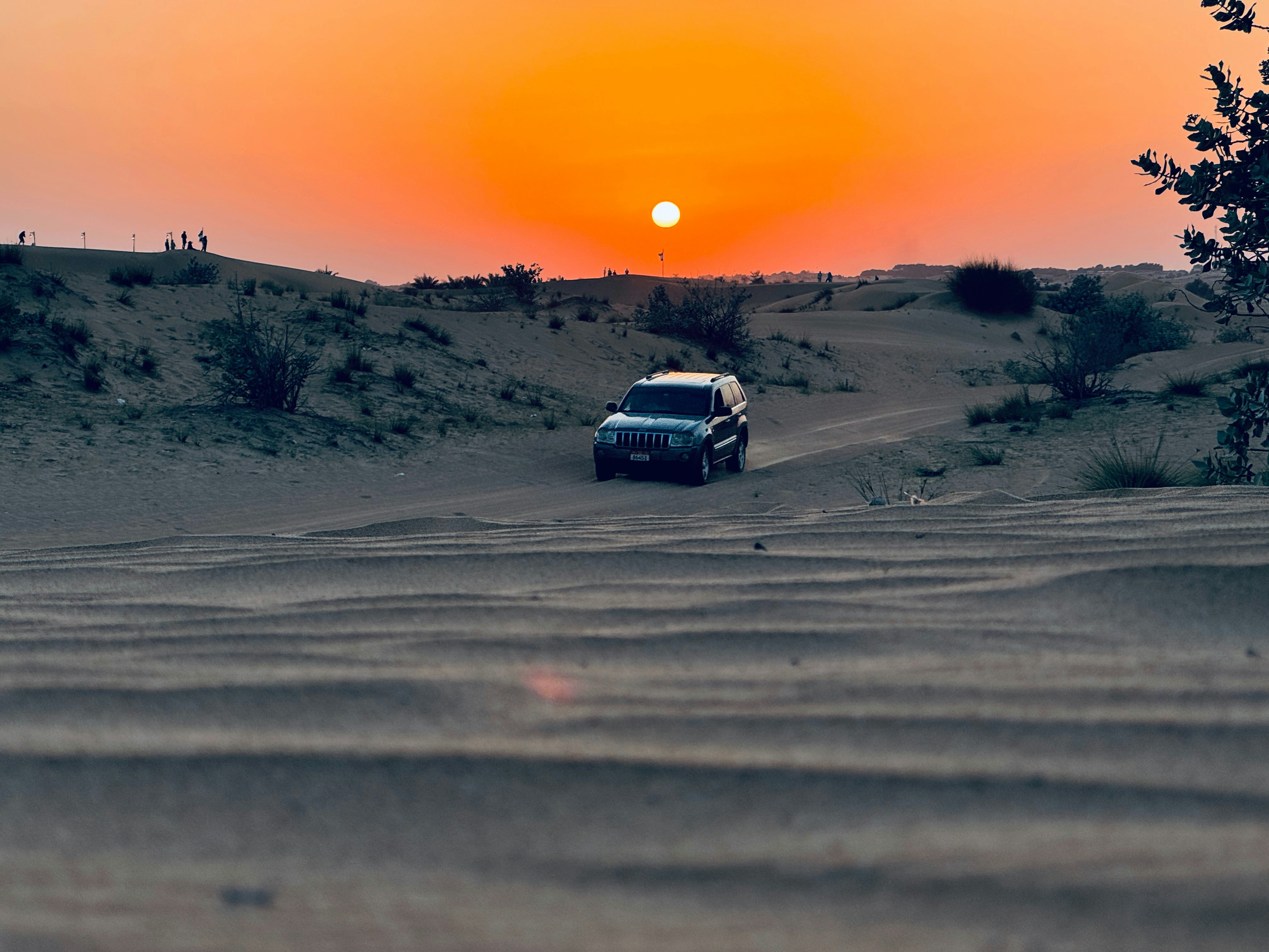a car driving through the desert at sunset
