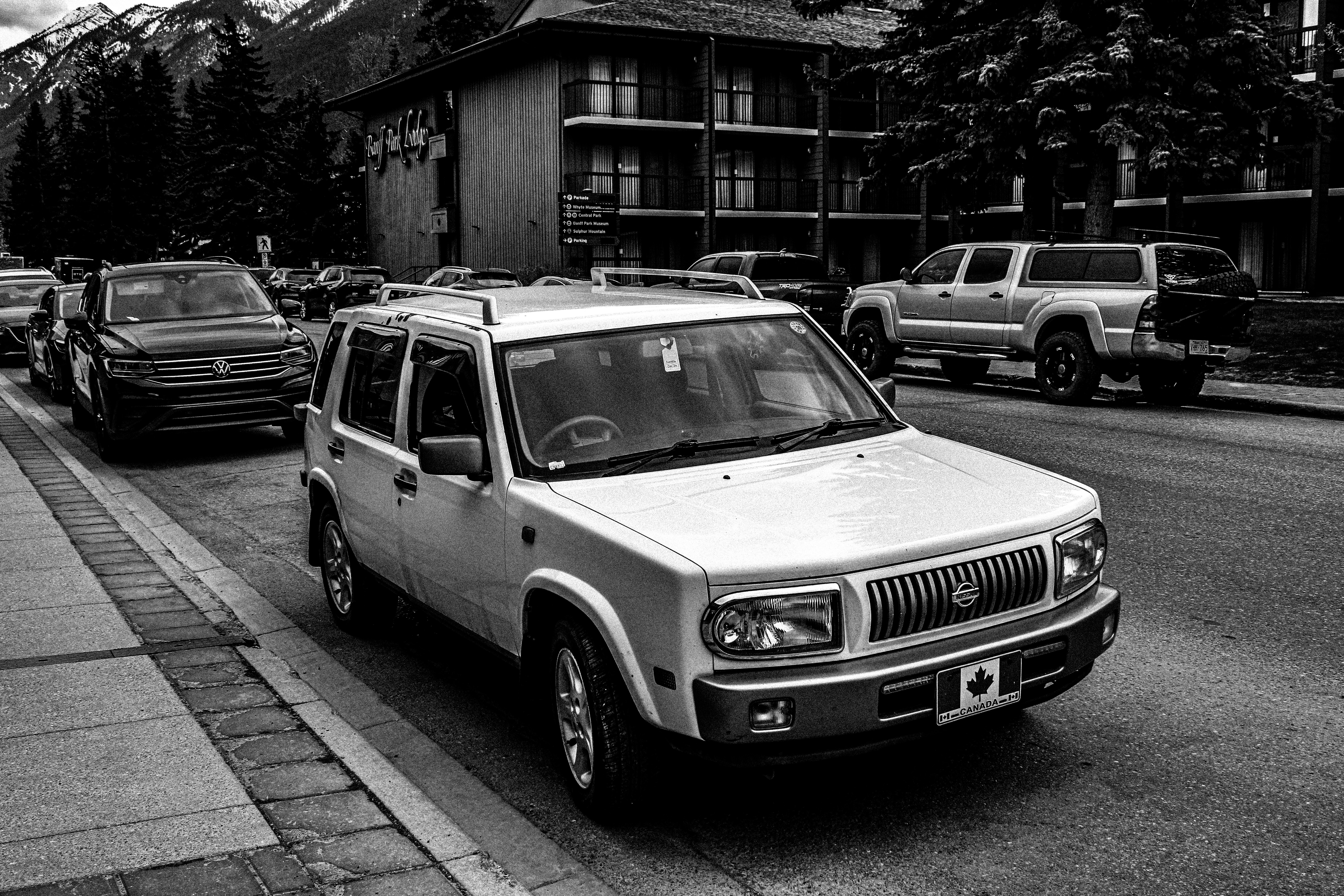 a black and white photo of cars parked on the side of the road