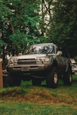 a truck parked in the grass next to a tree