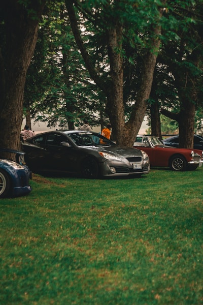 A row of parked cars sitting on top of a lush green field