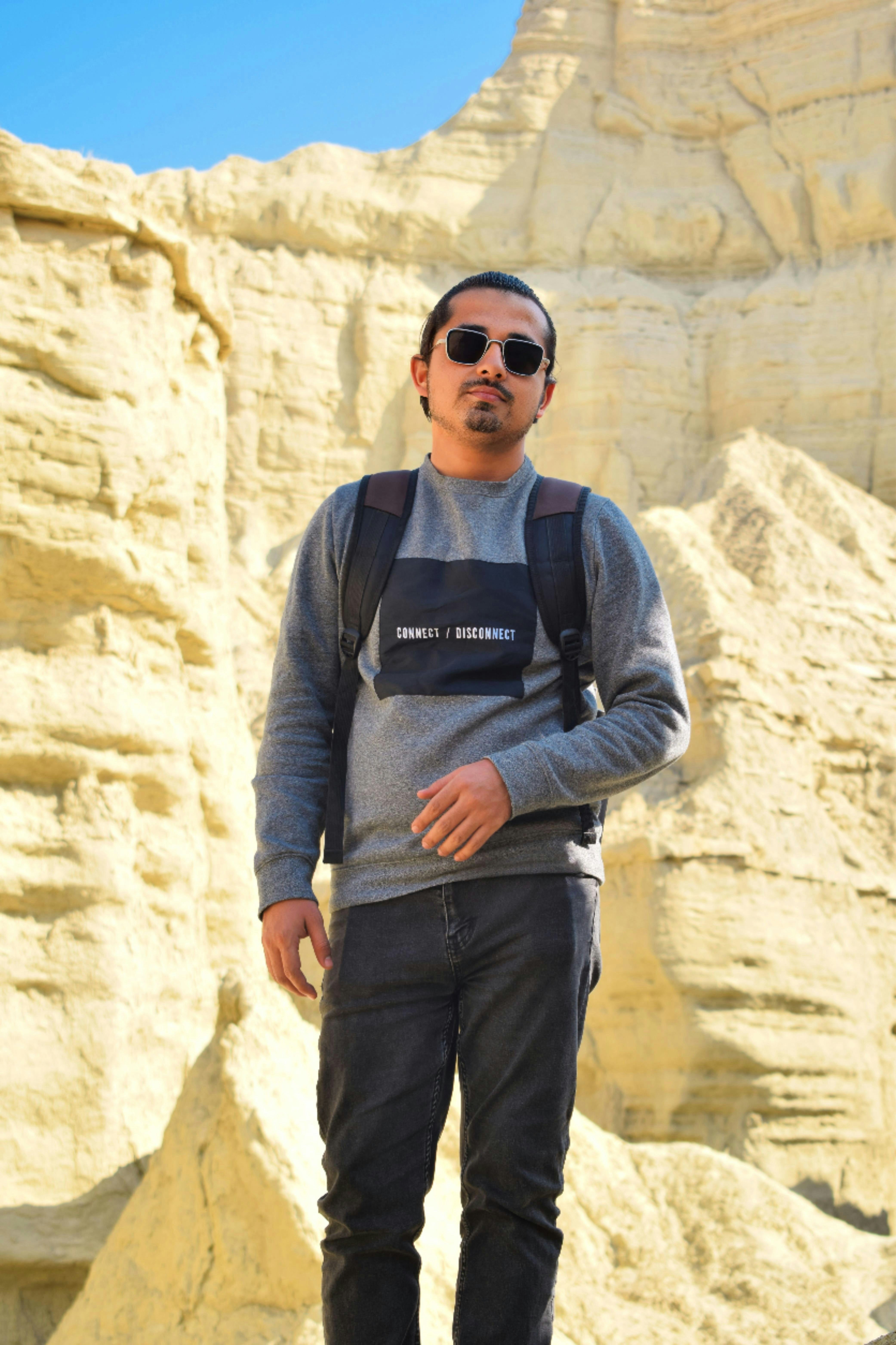 a man with a backpack standing in front of a mountain