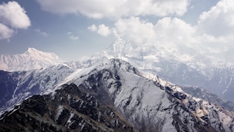 a snow covered mountain range under a cloudy sky
