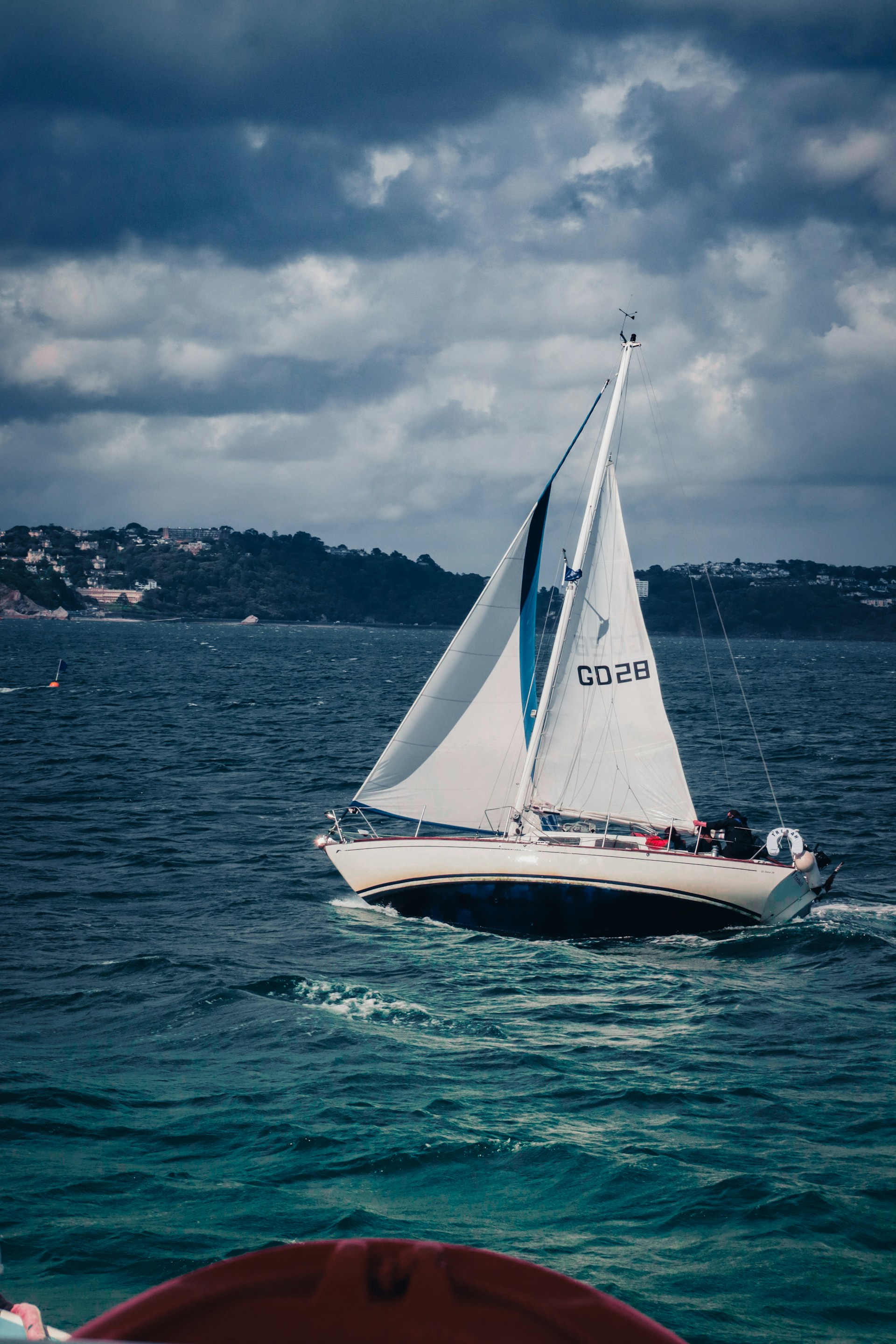 a sailboat sailing in the ocean on a cloudy day