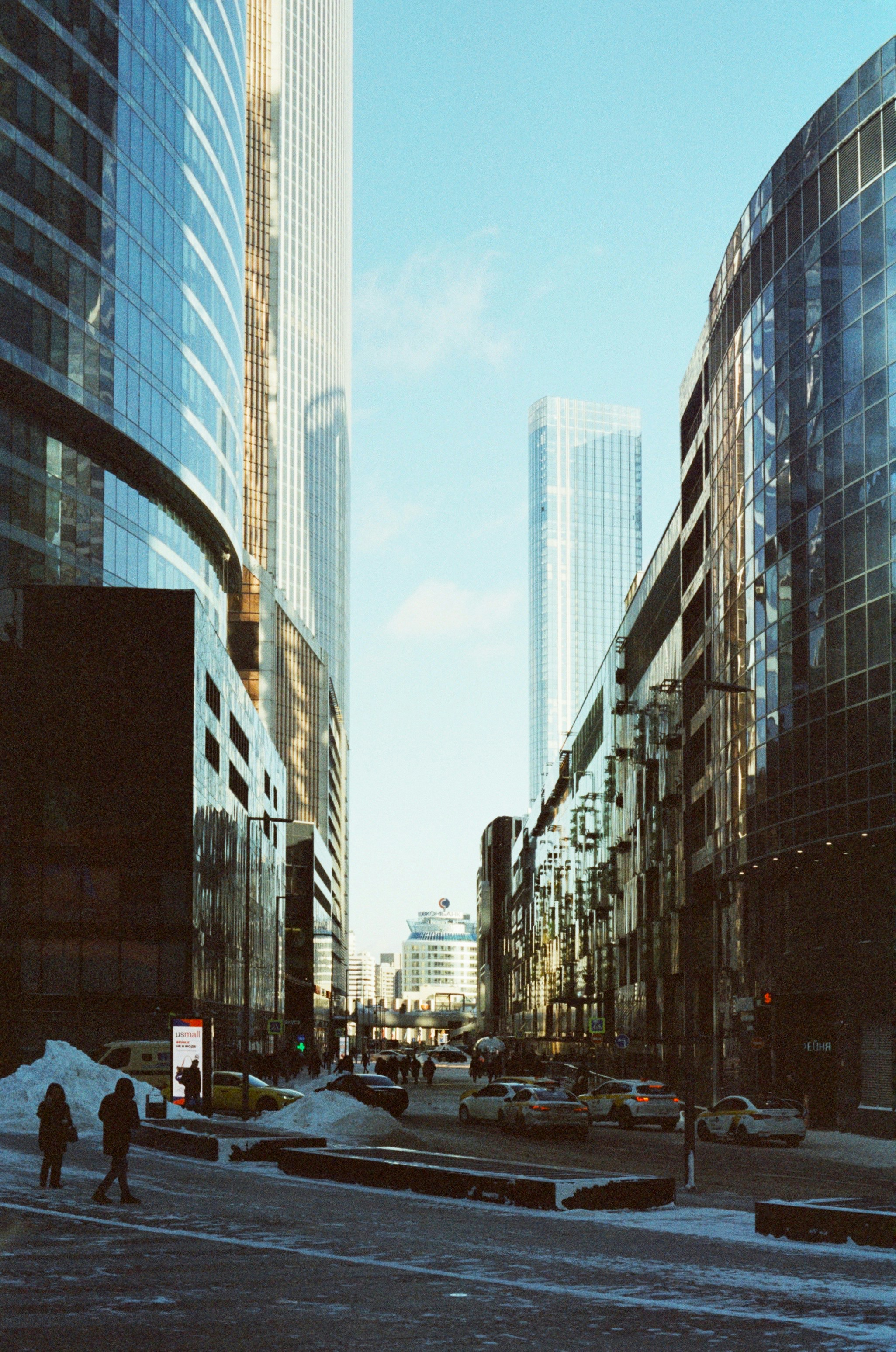 a couple of people walking down a street next to tall buildings