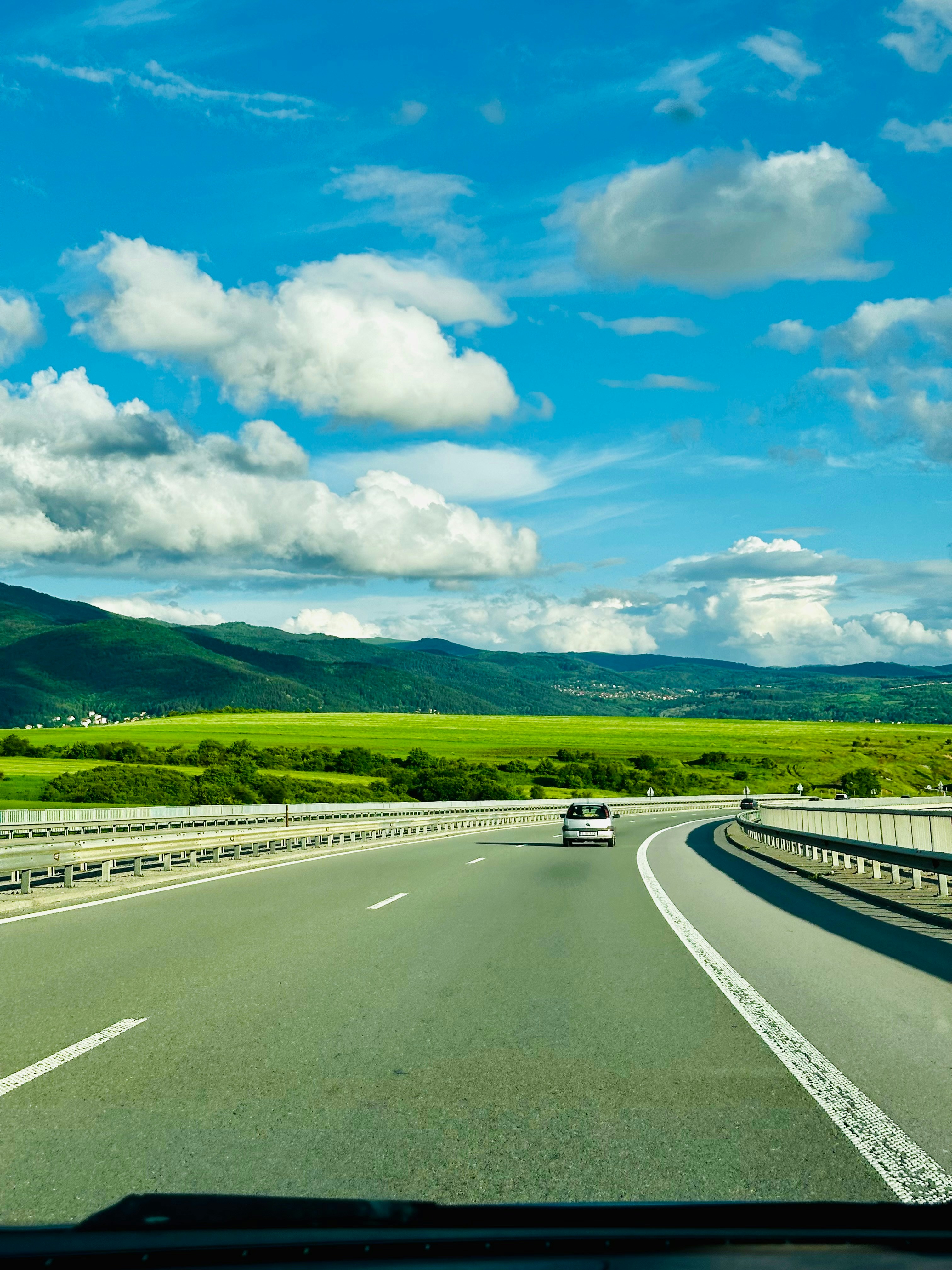 Car on an open highway road trip with scenic landscape and clear blue sky
