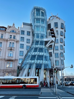 a red and white bus driving past a tall building