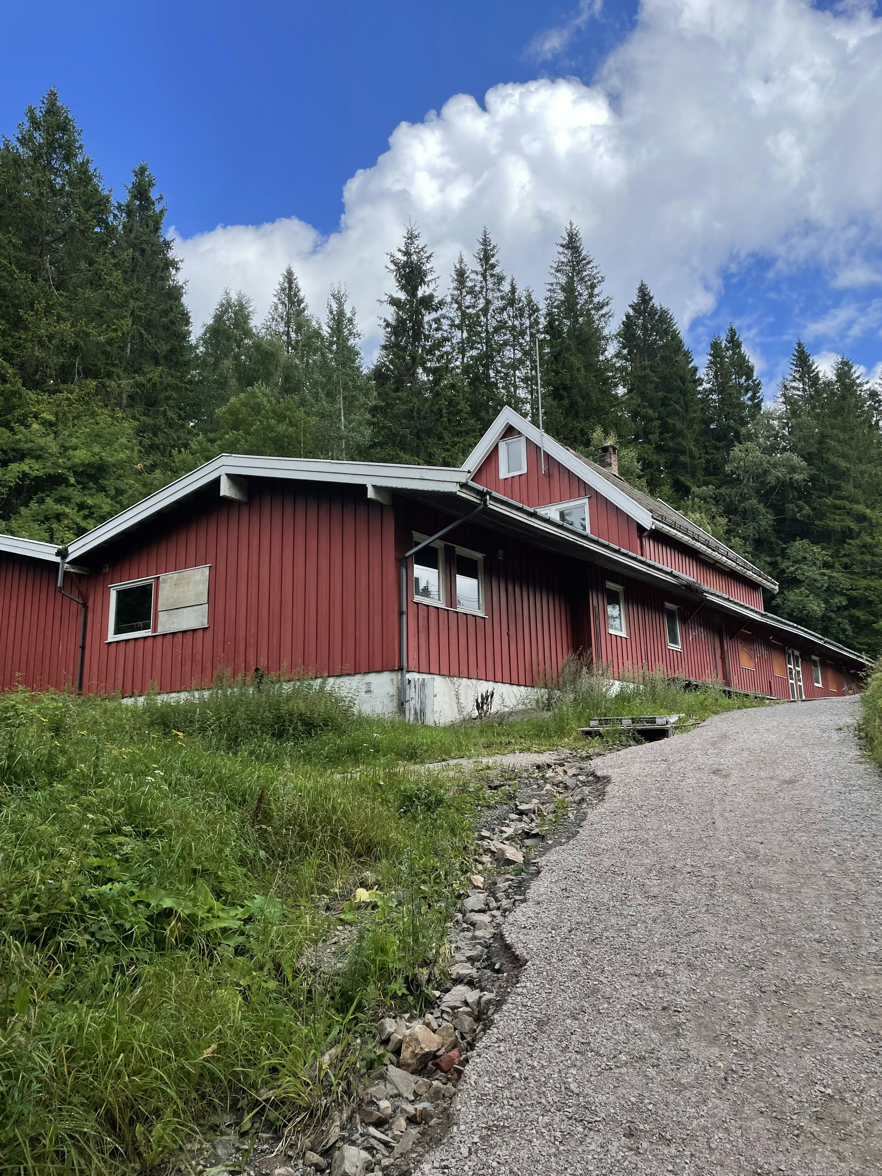 a red house sitting on top of a lush green hillside