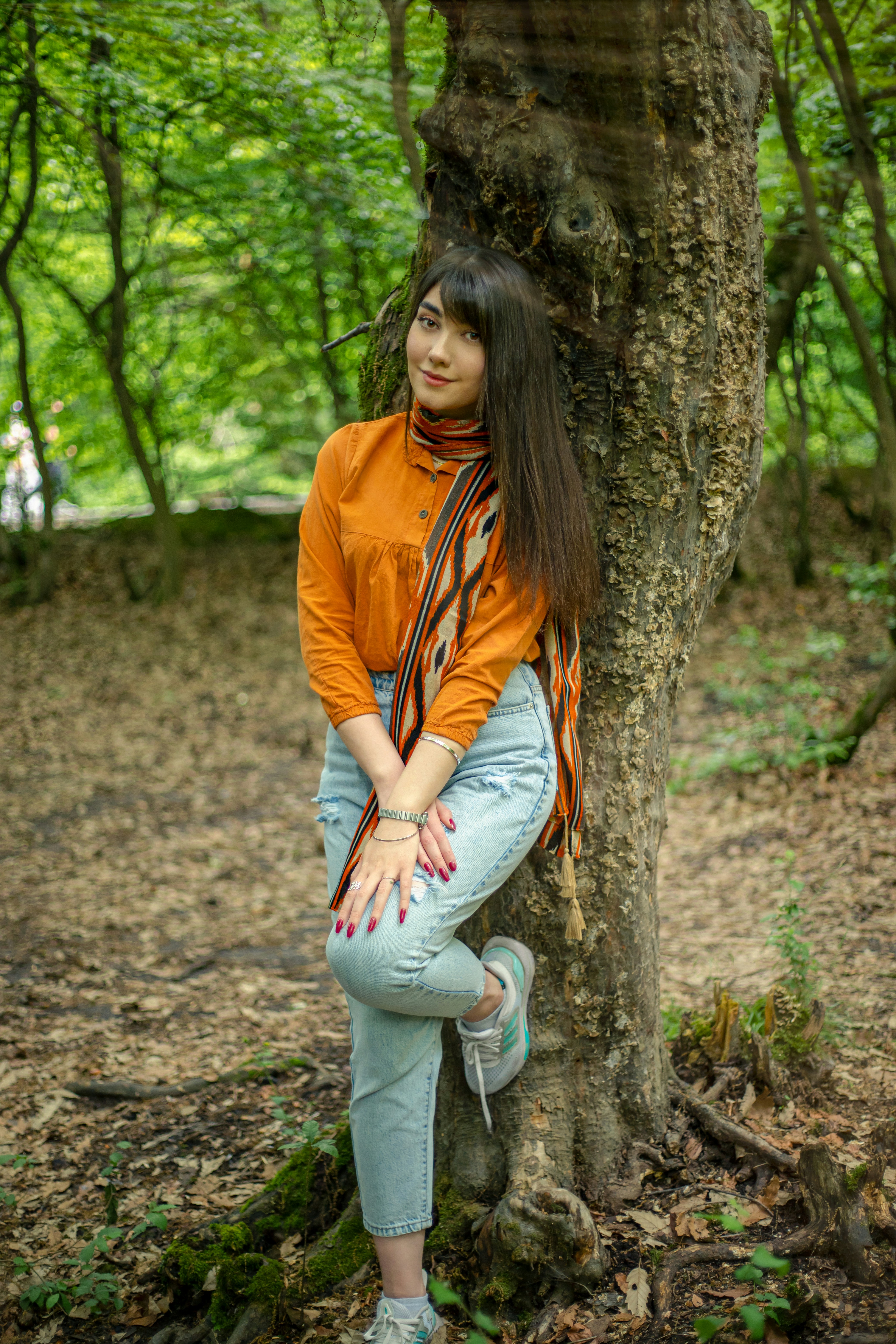 a woman leaning against a tree in the woods