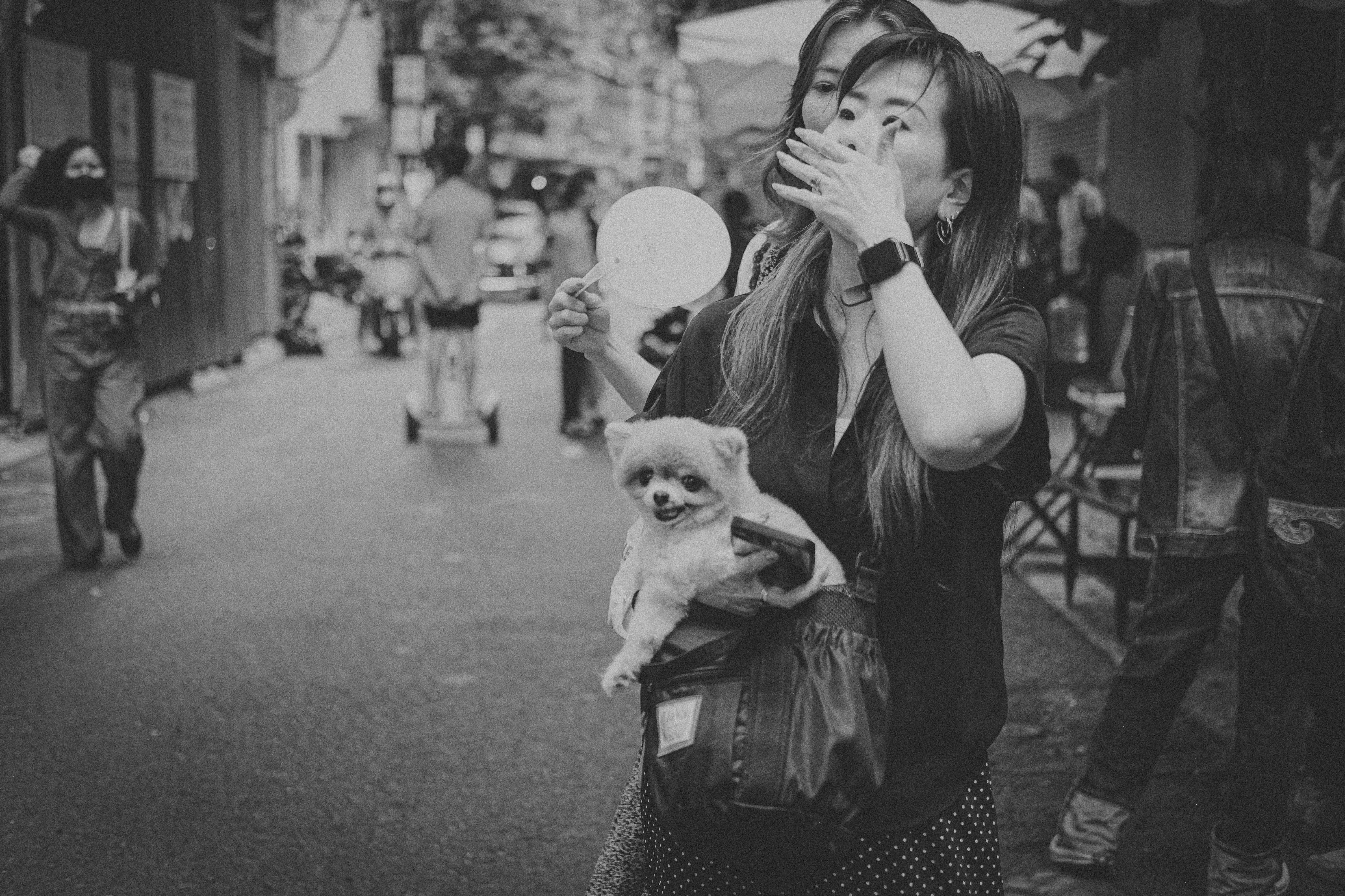 a black and white photo of a woman holding a small dog