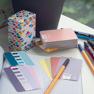 a desk with a notebook, pens, and a box of cards