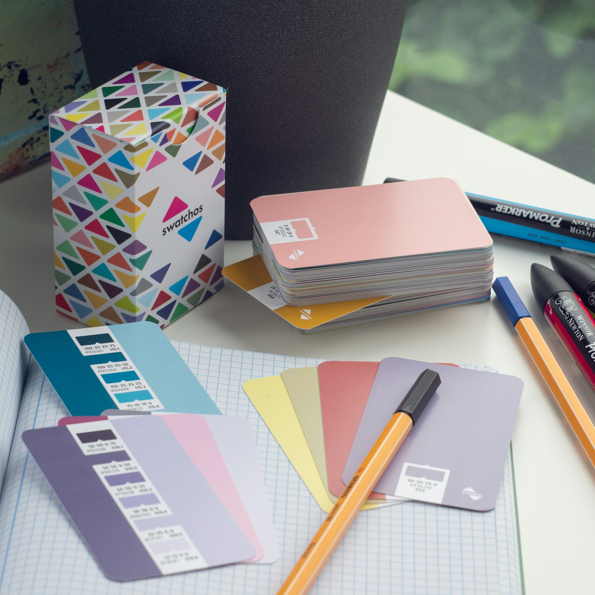 a desk with a notebook, pens, and a box of cards