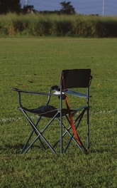a couple of chairs sitting on top of a lush green field