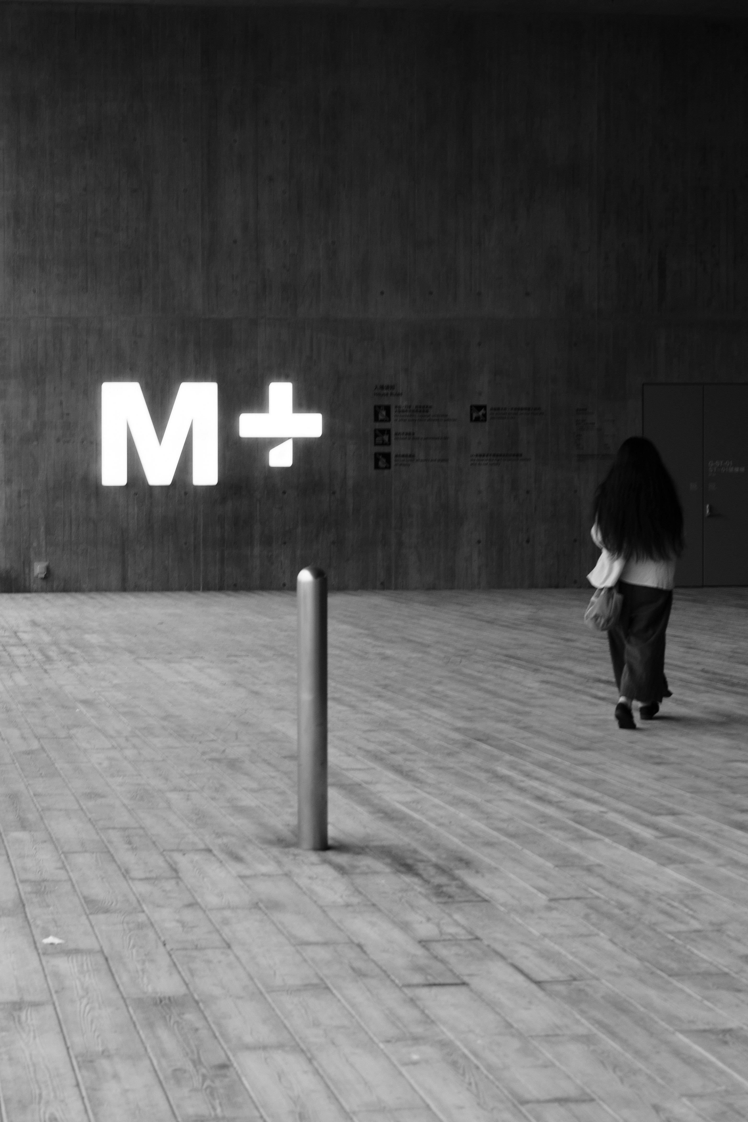 a woman walking down a sidewalk next to a tall building