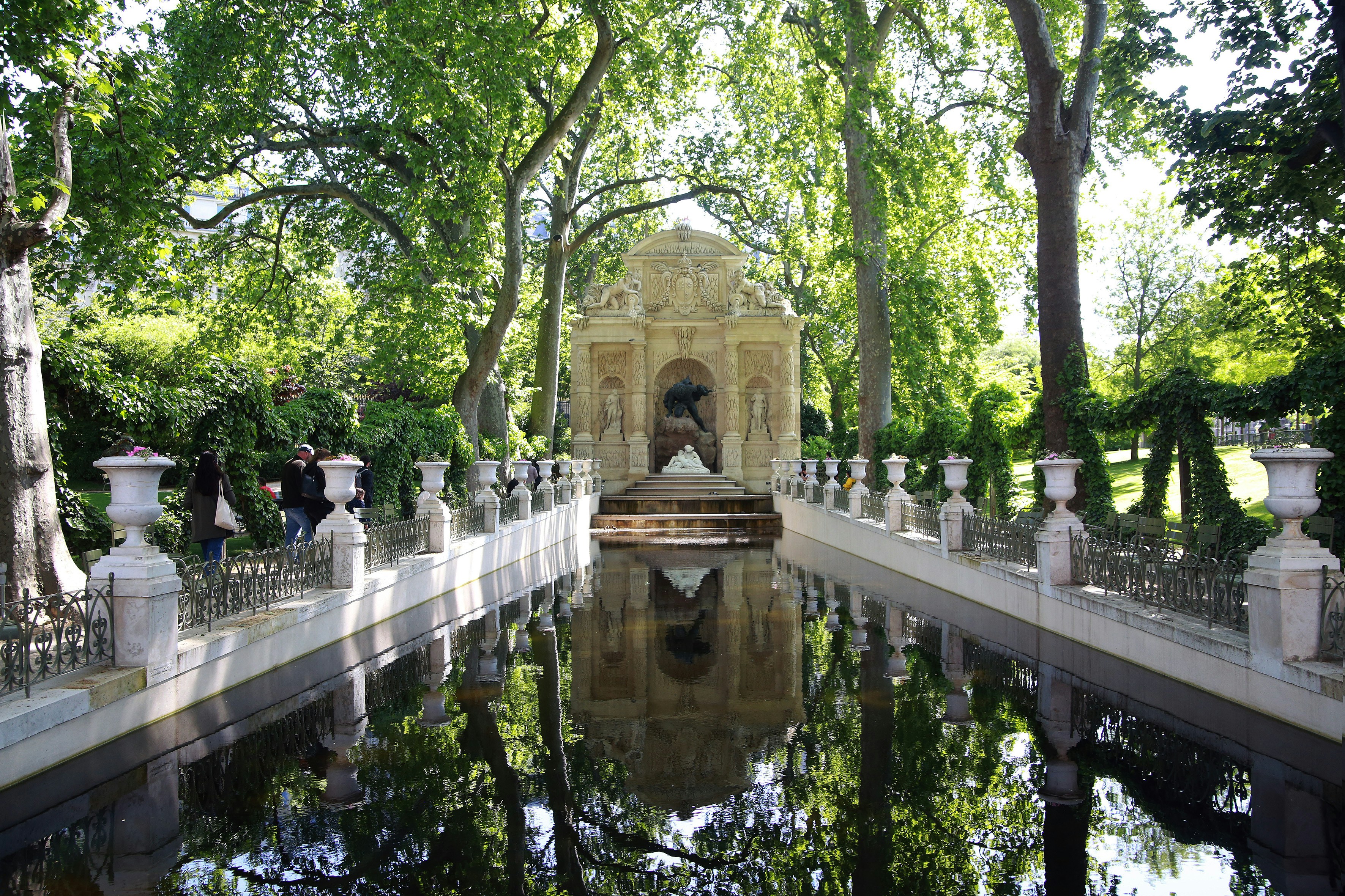un piccolo laghetto circondato da alberi e statue