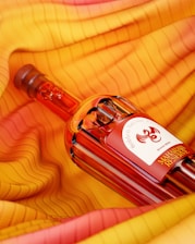a bottle of red wine sitting on top of a yellow cloth
