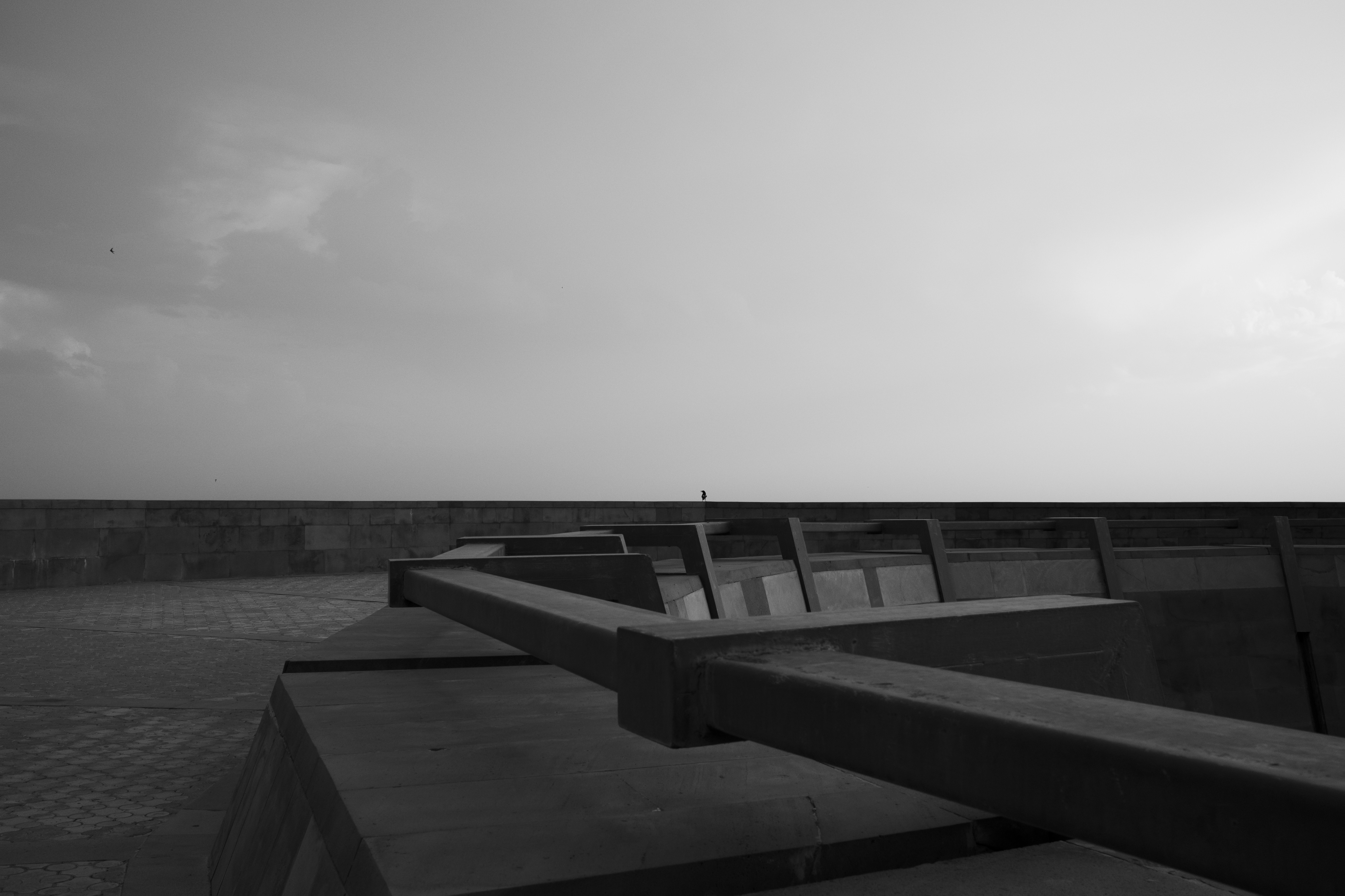 a black and white photo of a bench near the ocean