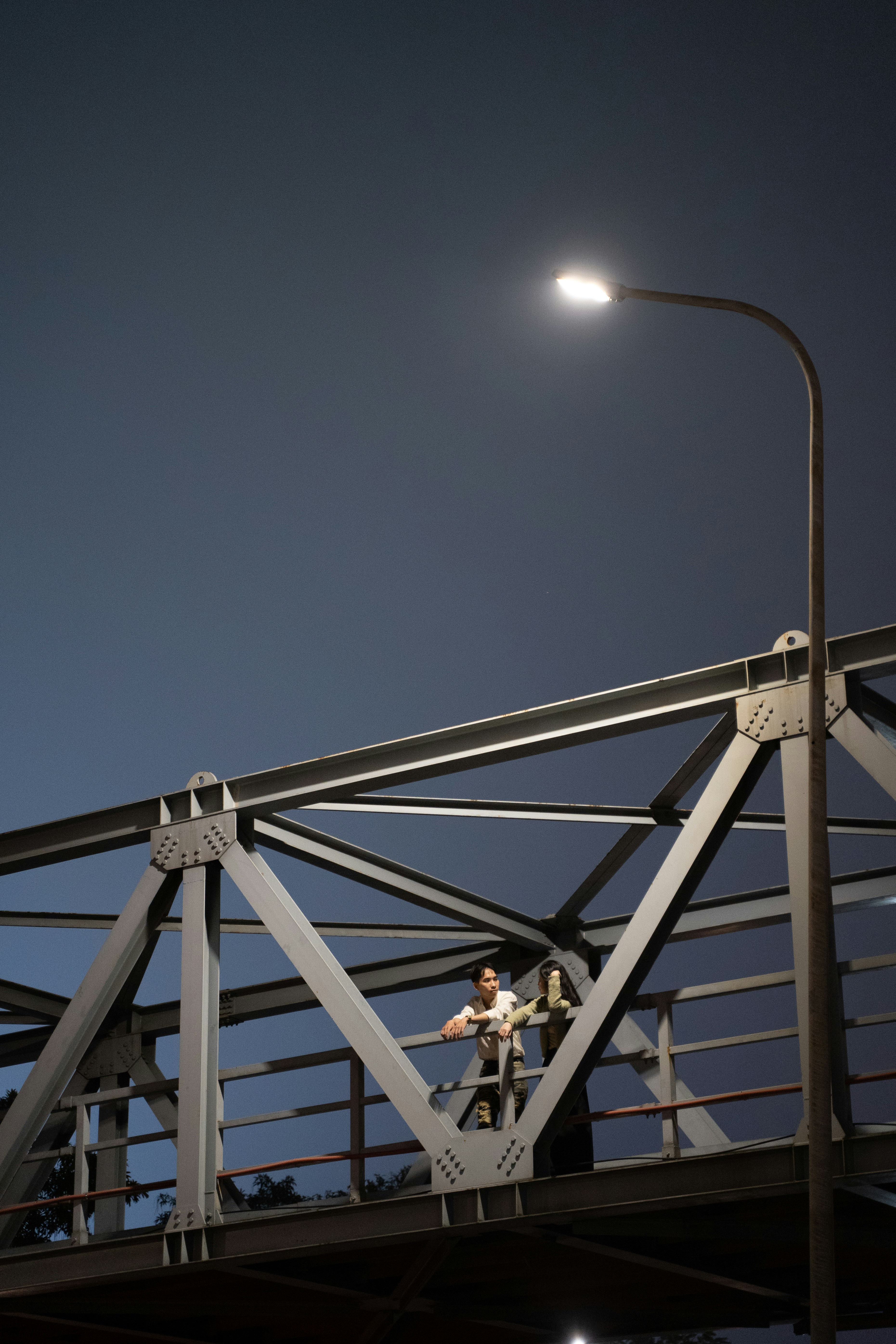 a man standing on a metal bridge under a street light