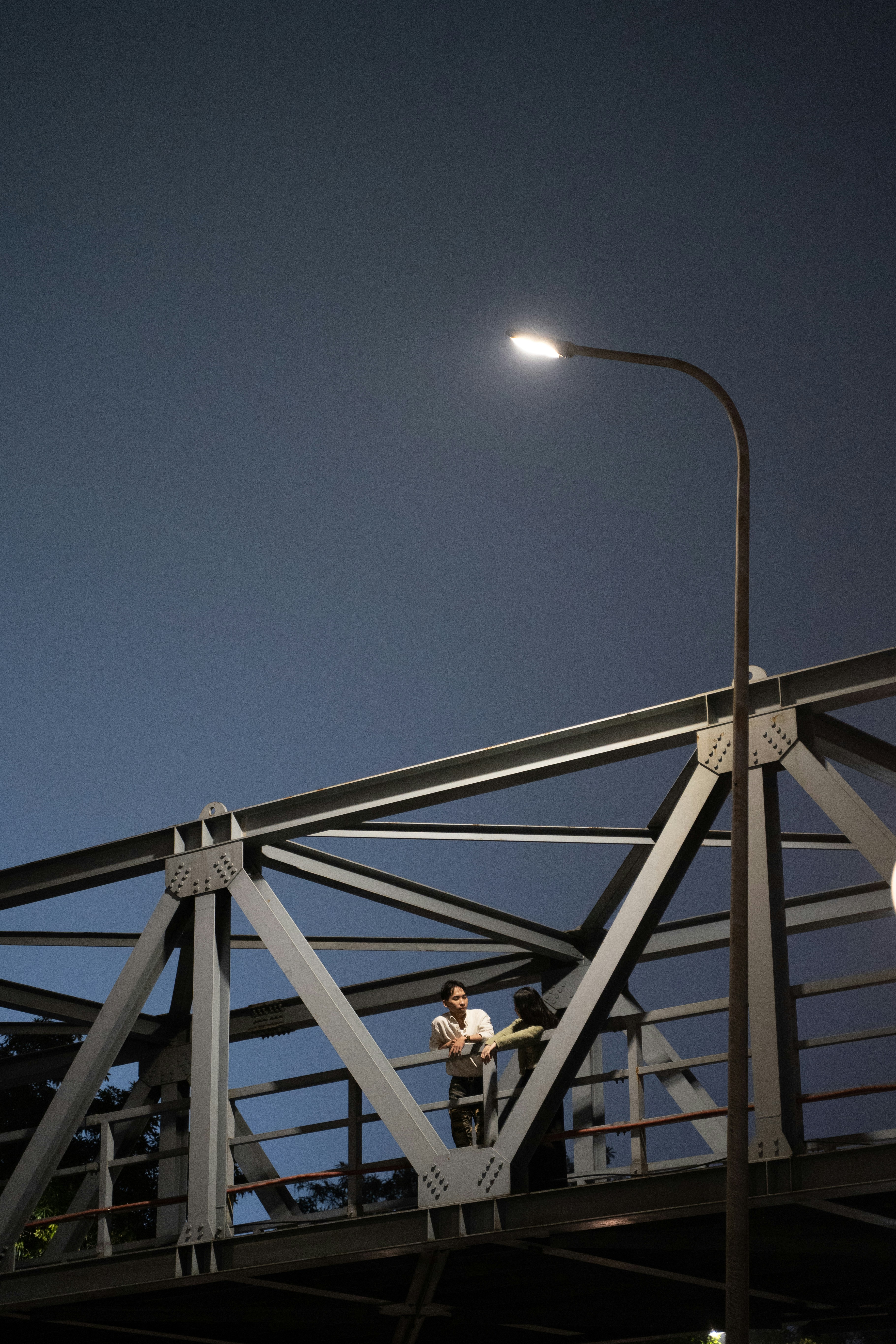 a man standing on a bridge under a street light