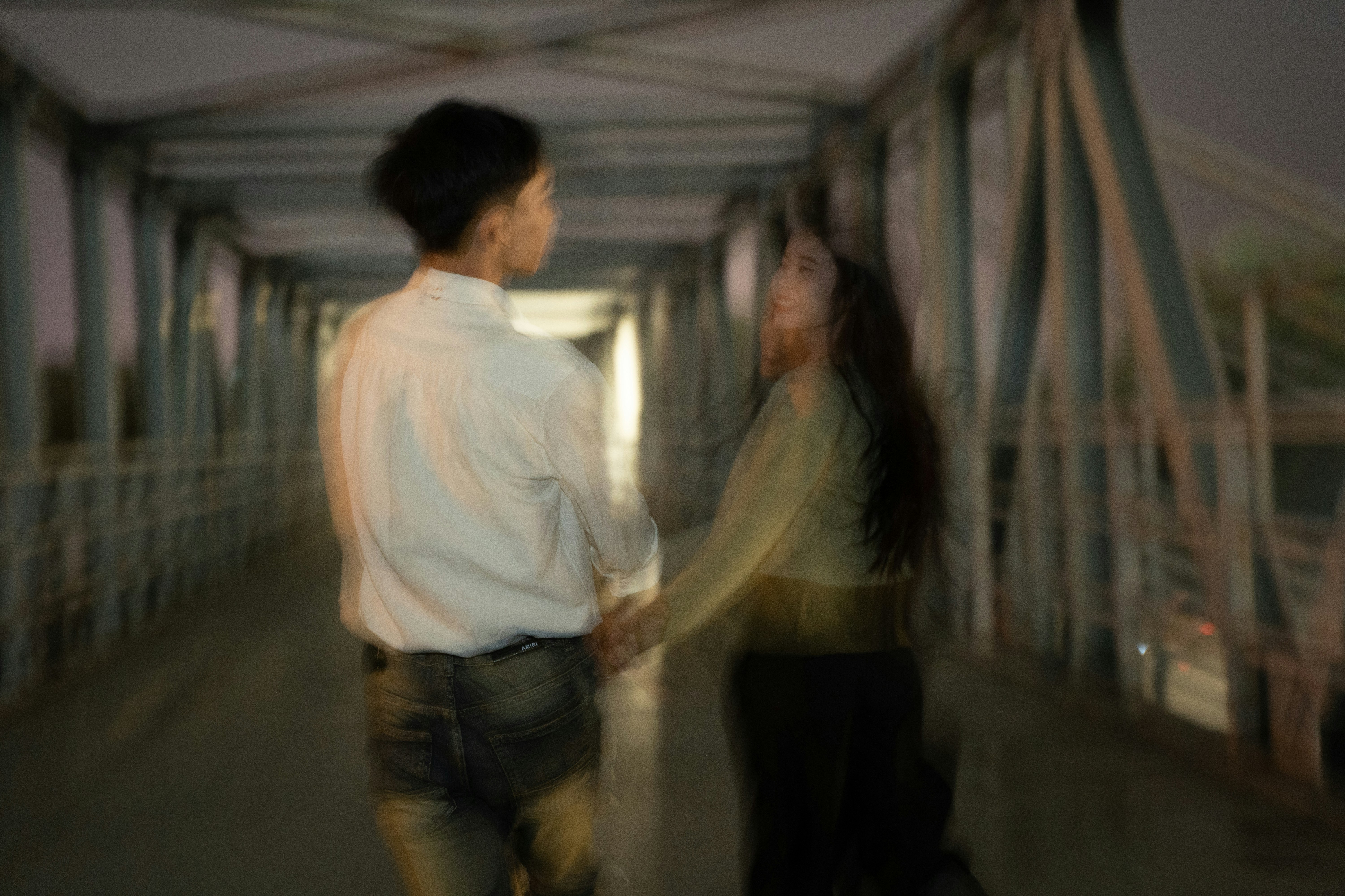 a man and a woman walking down a bridge