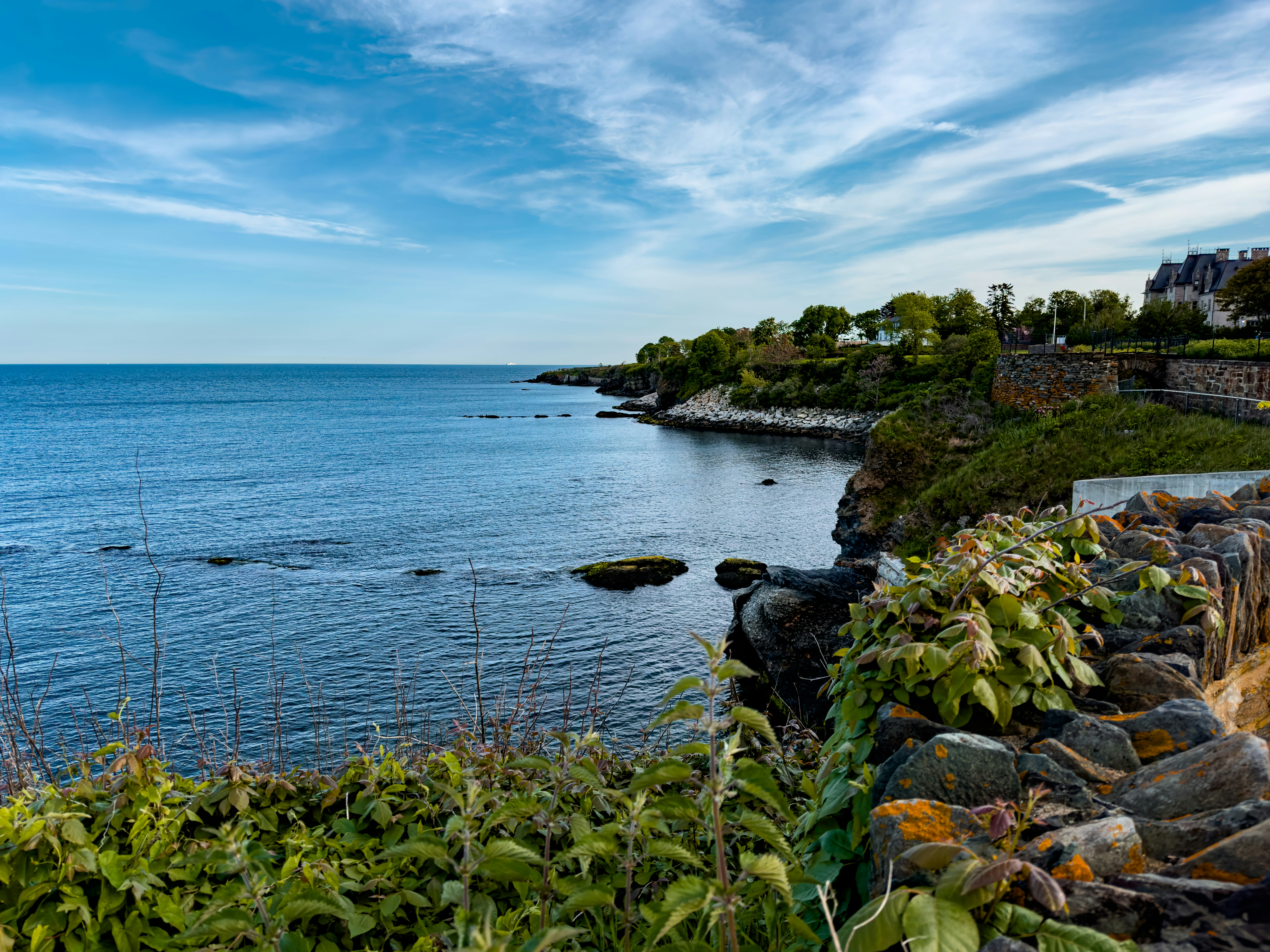 a body of water surrounded by a lush green hillside, Middle of the Newport Cliffwalk