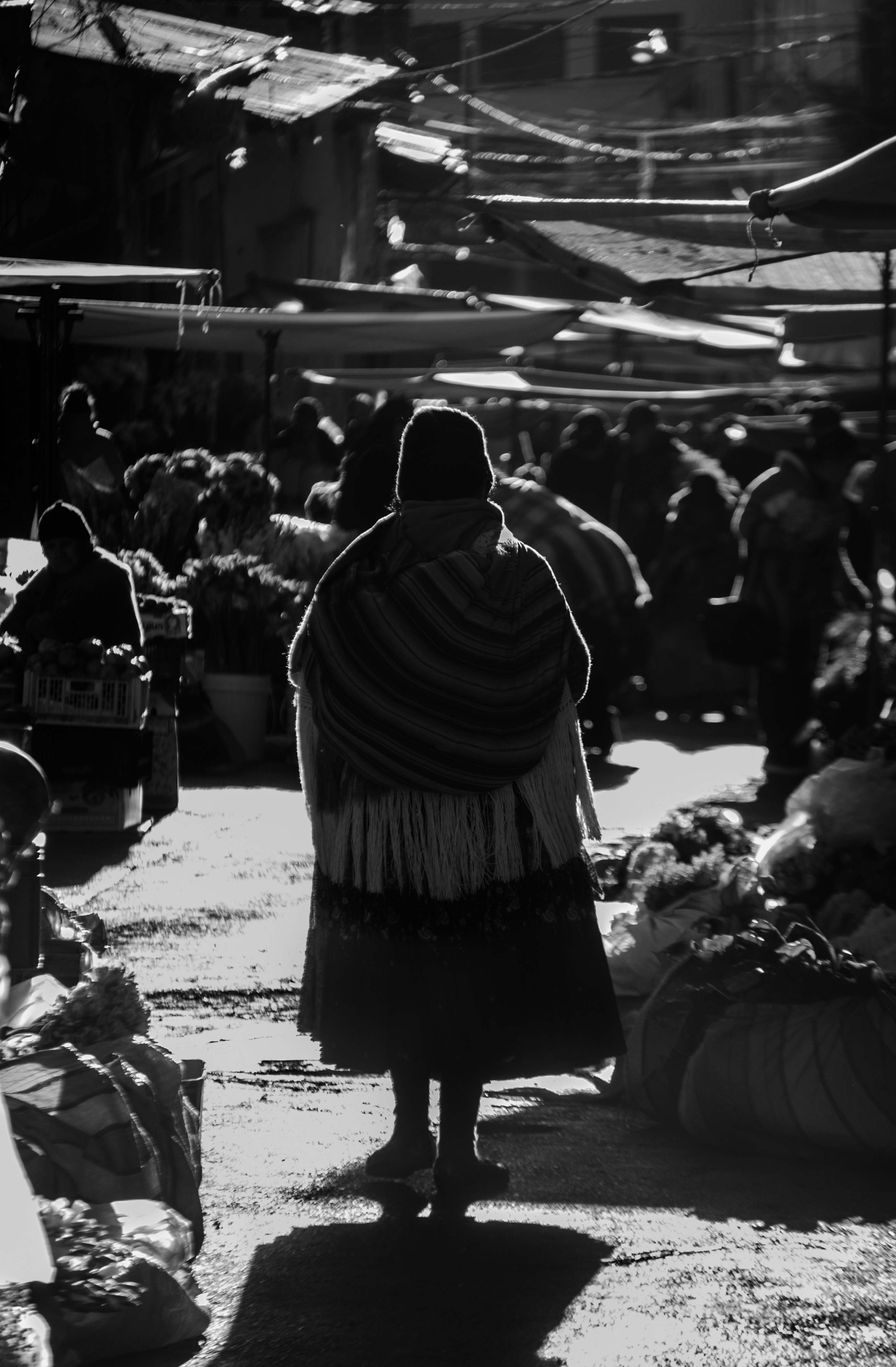 a woman walking through a market with lots of produce