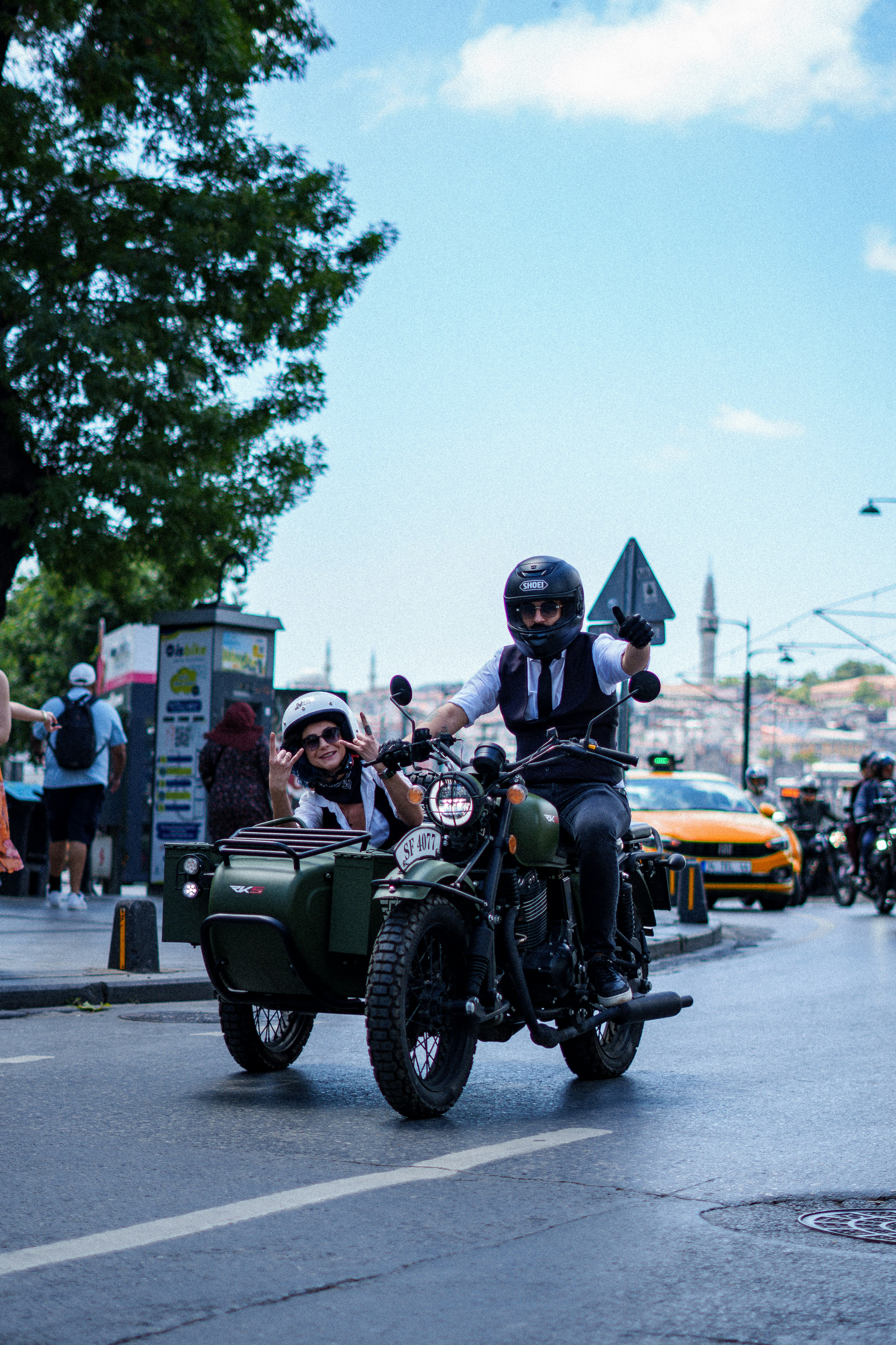 Man and woman riding a vintage motorcycle with a sidecar.