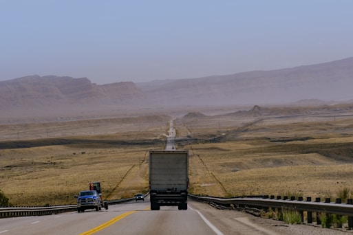 a semi truck driving down a highway in the desert