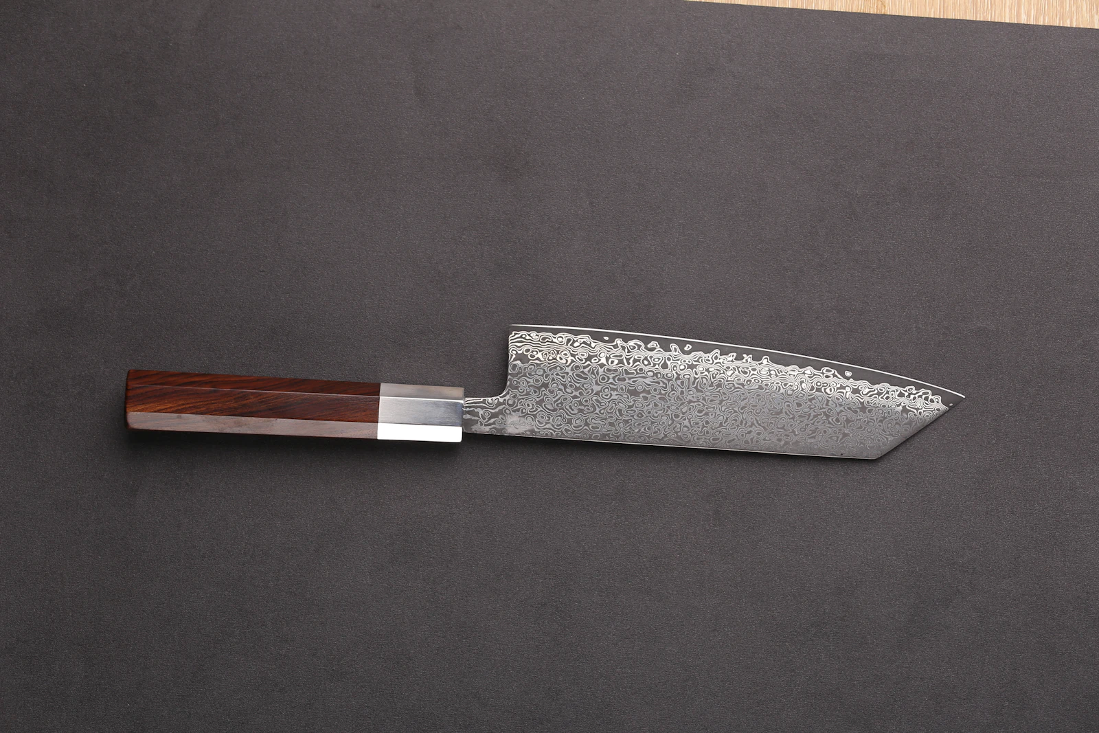 Damascus bunka knife with an octagonal rosewood handle on dark grey
