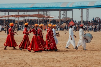 a group of people walking across a dirt field