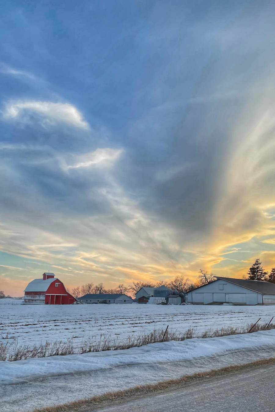 Red barn standing in a snow-covered field on an Iowa farm, showing how spread out the state is for anyone using an Iowa dating app