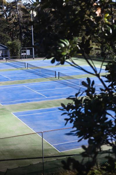a tennis court with several tennis courts surrounded by trees