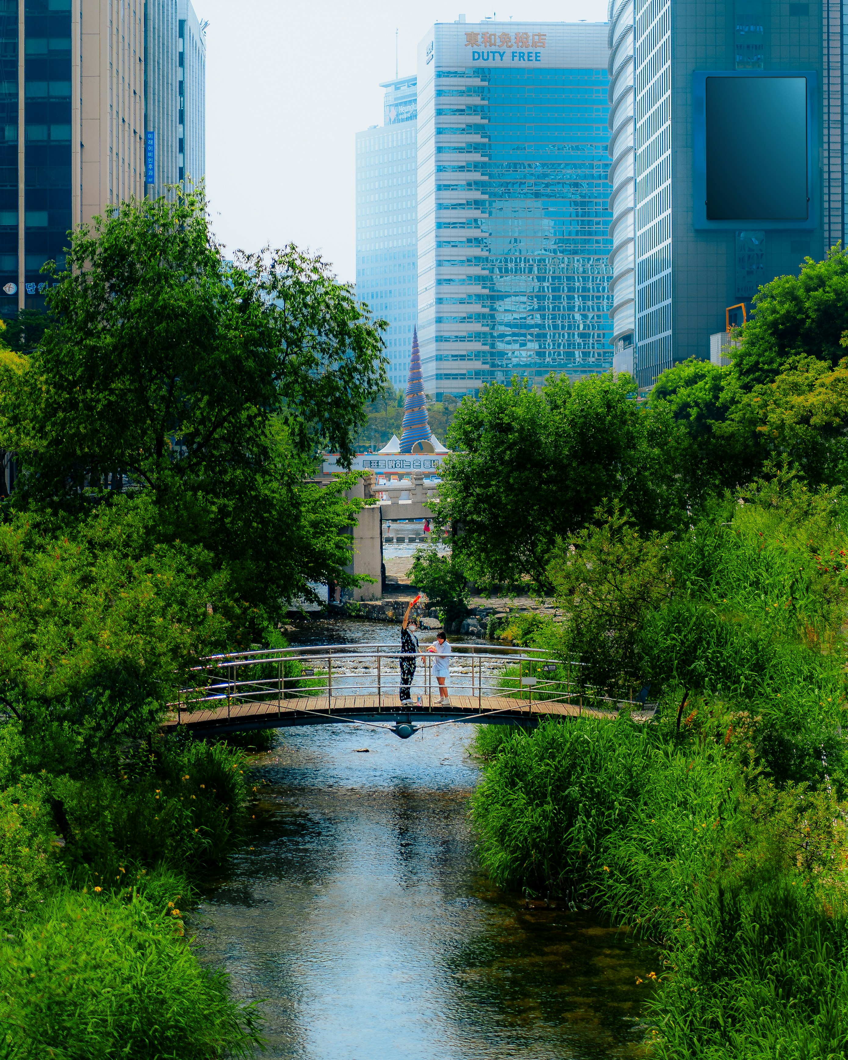 a couple of people standing on a bridge over a river