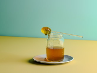 a glass jar filled with honey sitting on a plate