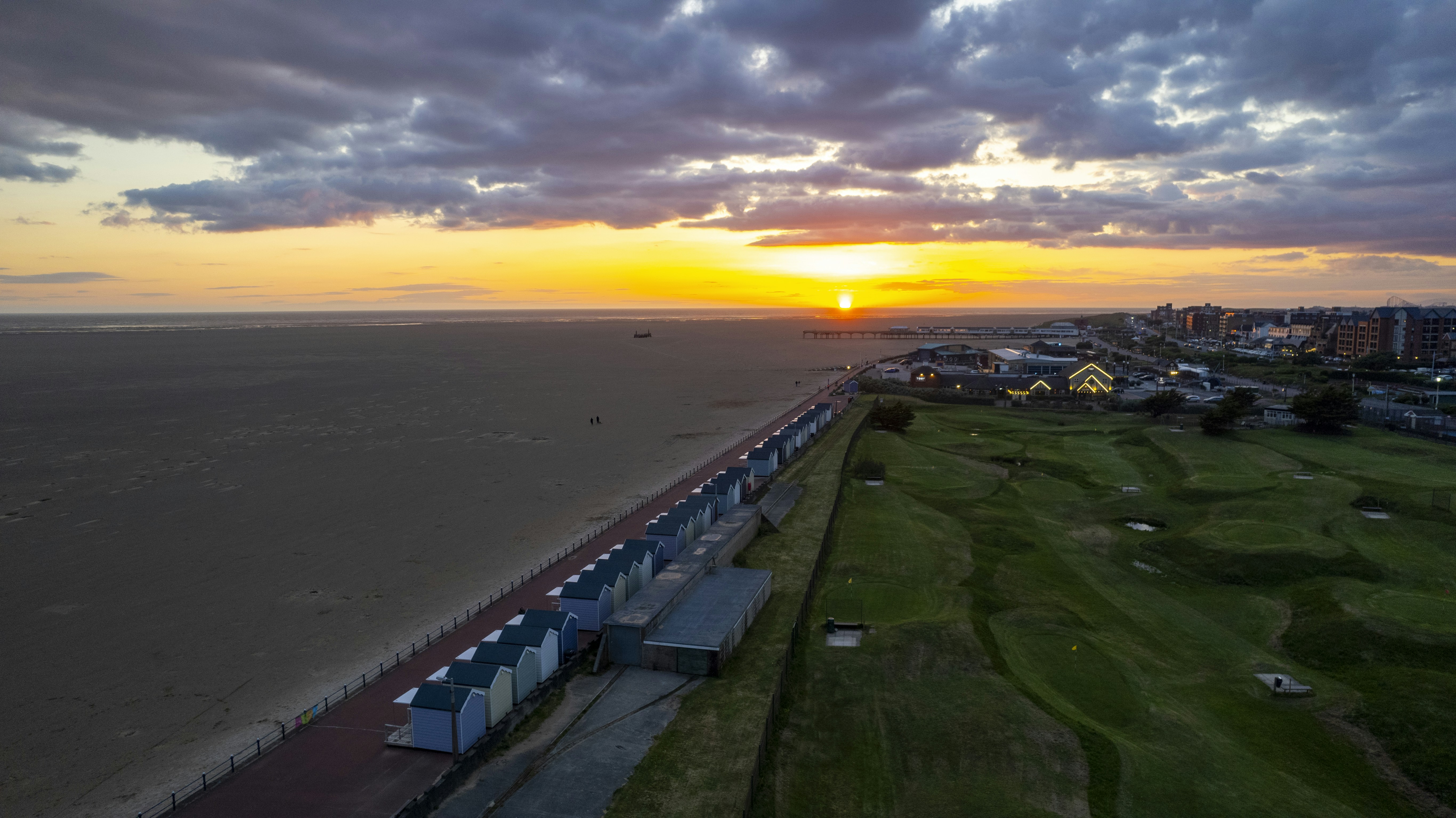 Die Sonne geht über einem Strand und einem Golfplatz unter