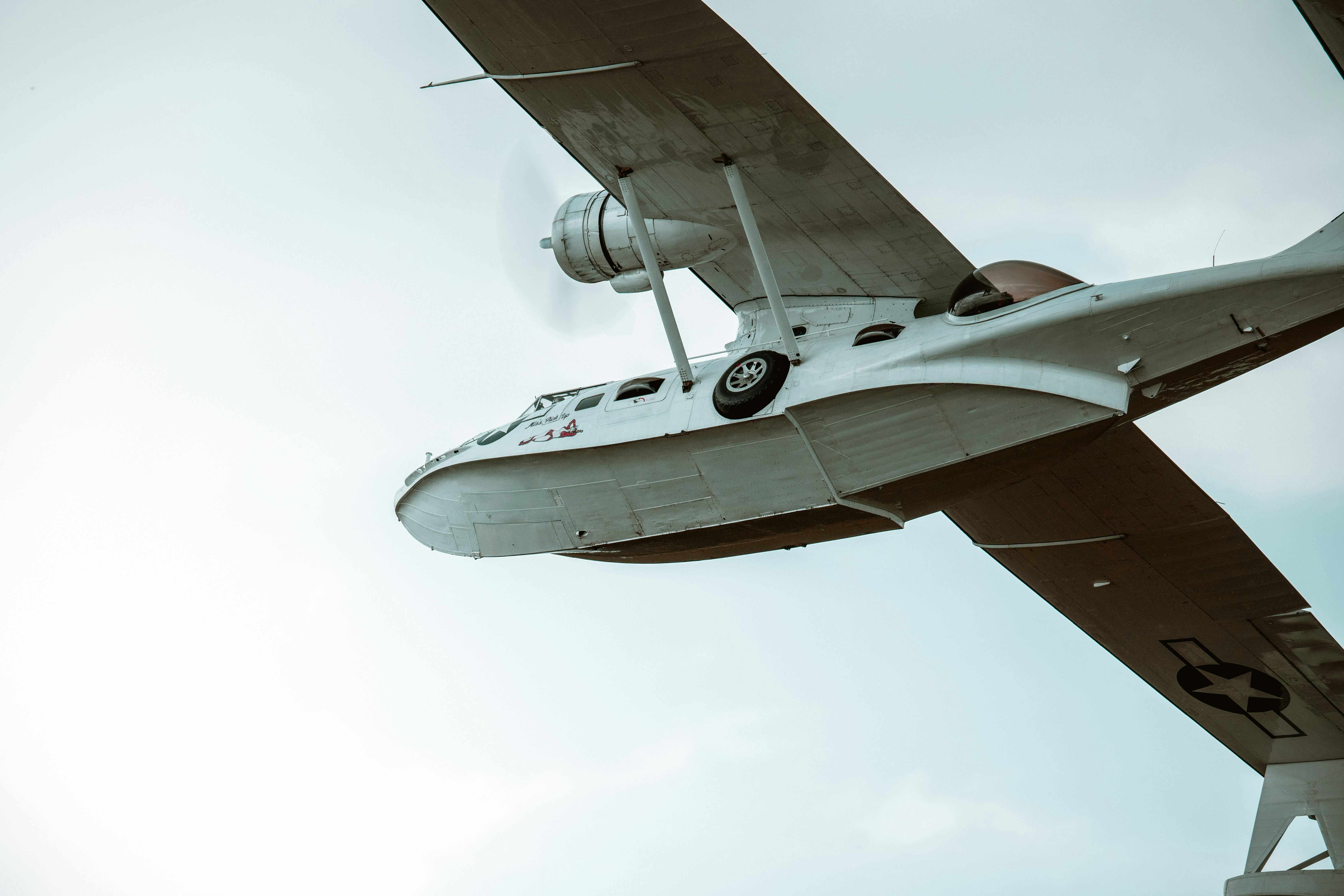 a small airplane flying through a cloudy blue sky, 