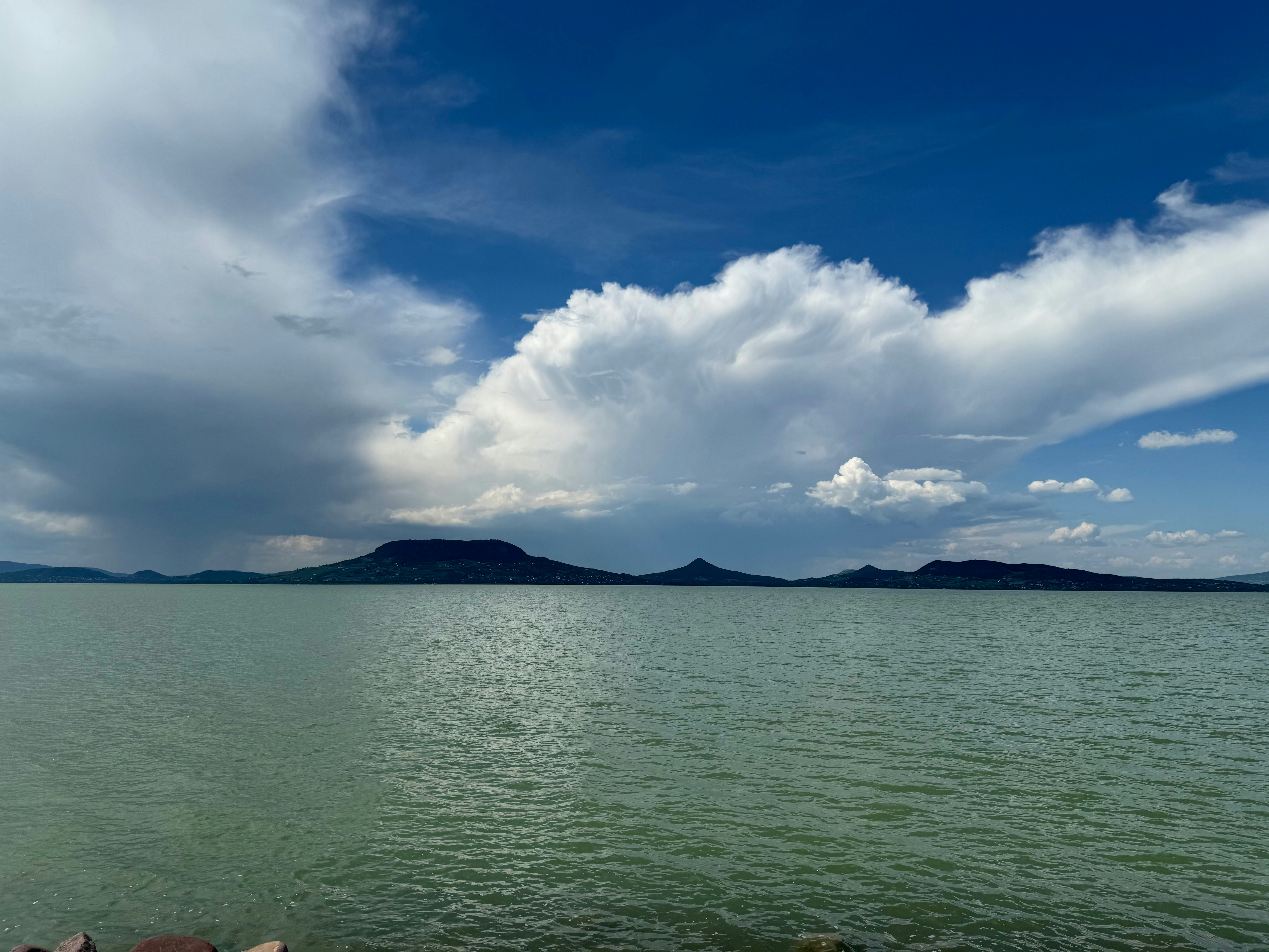 a large body of water under a cloudy blue sky