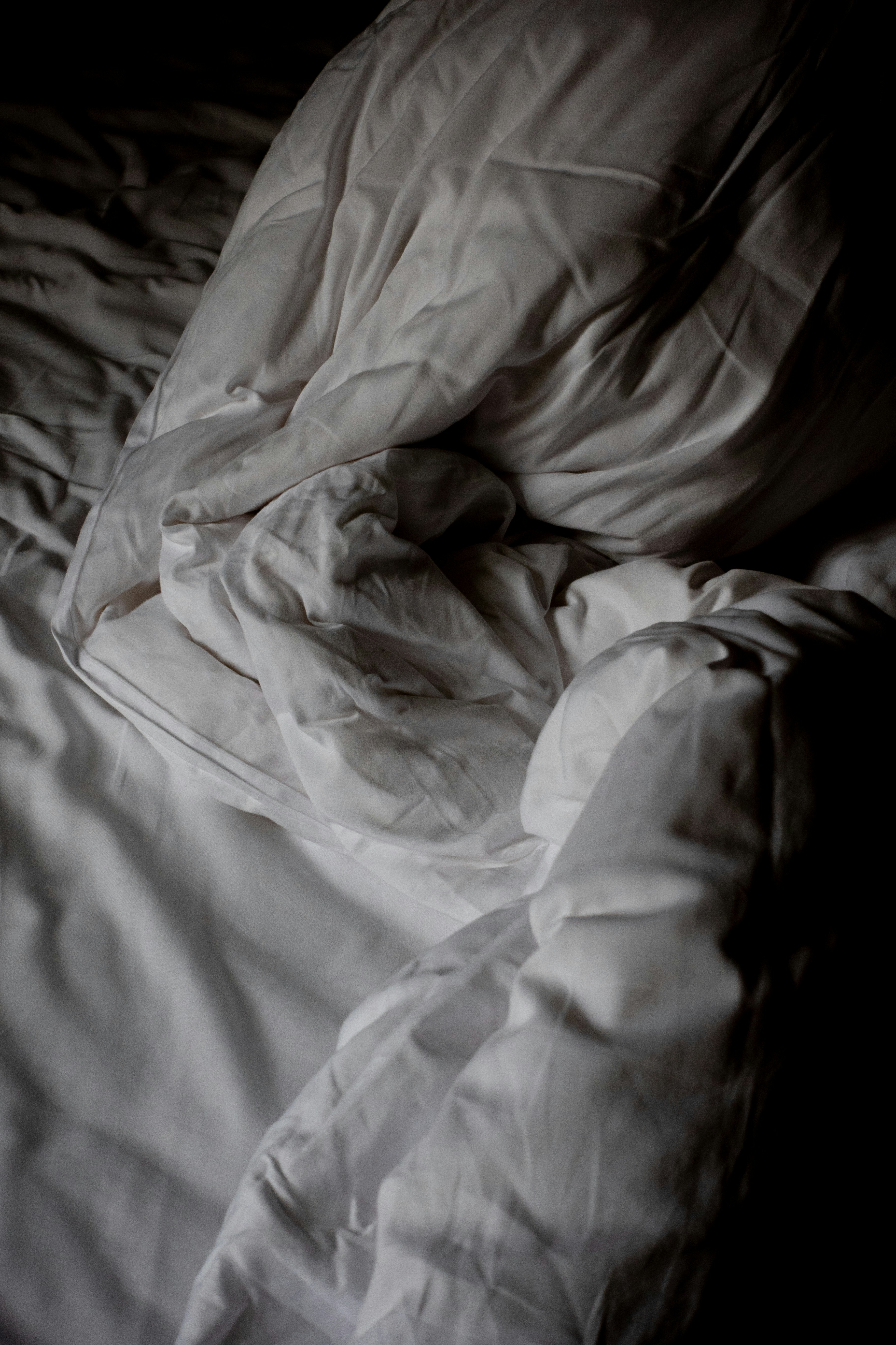 an unmade bed with white sheets and pillows