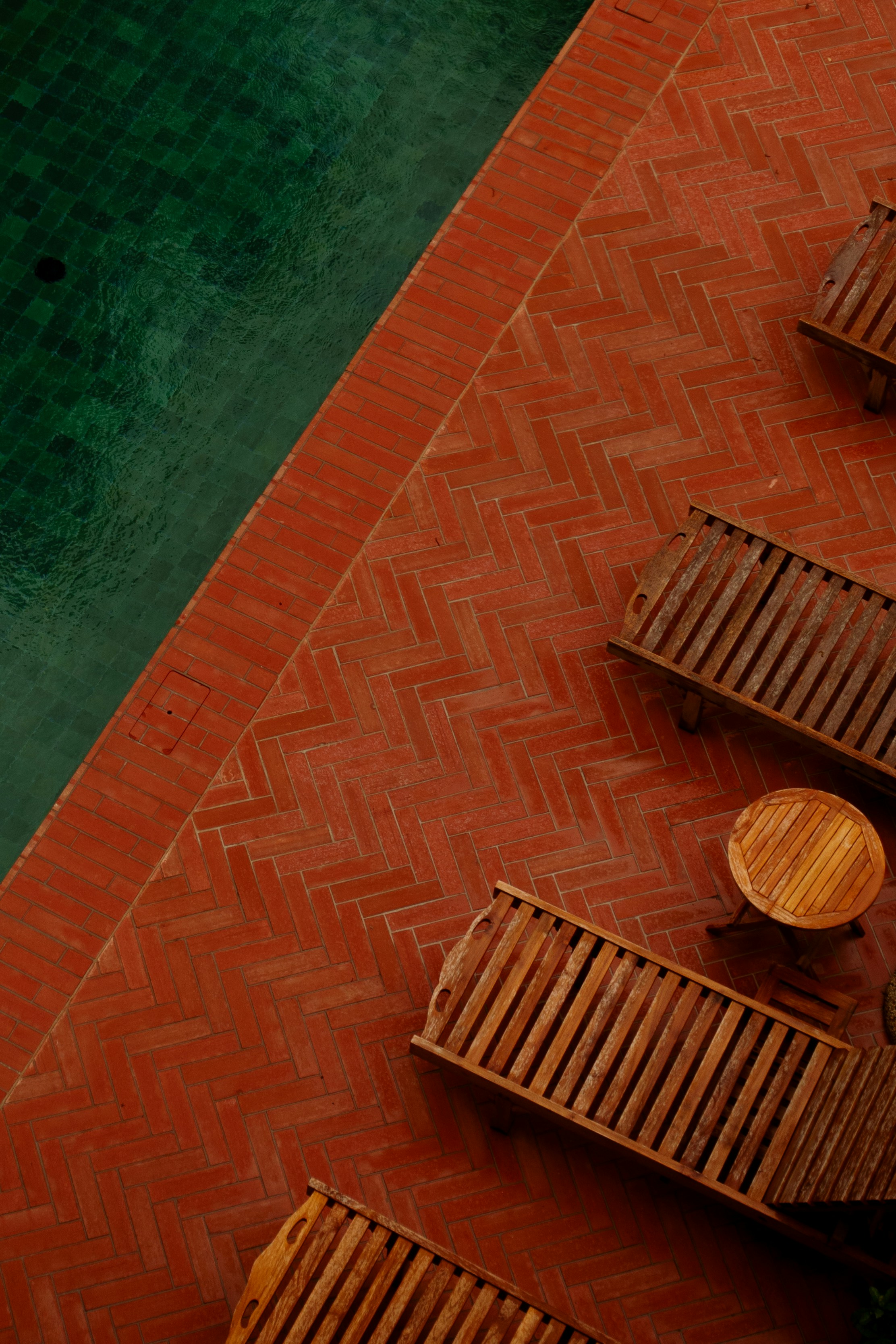 a row of wooden benches next to a pool