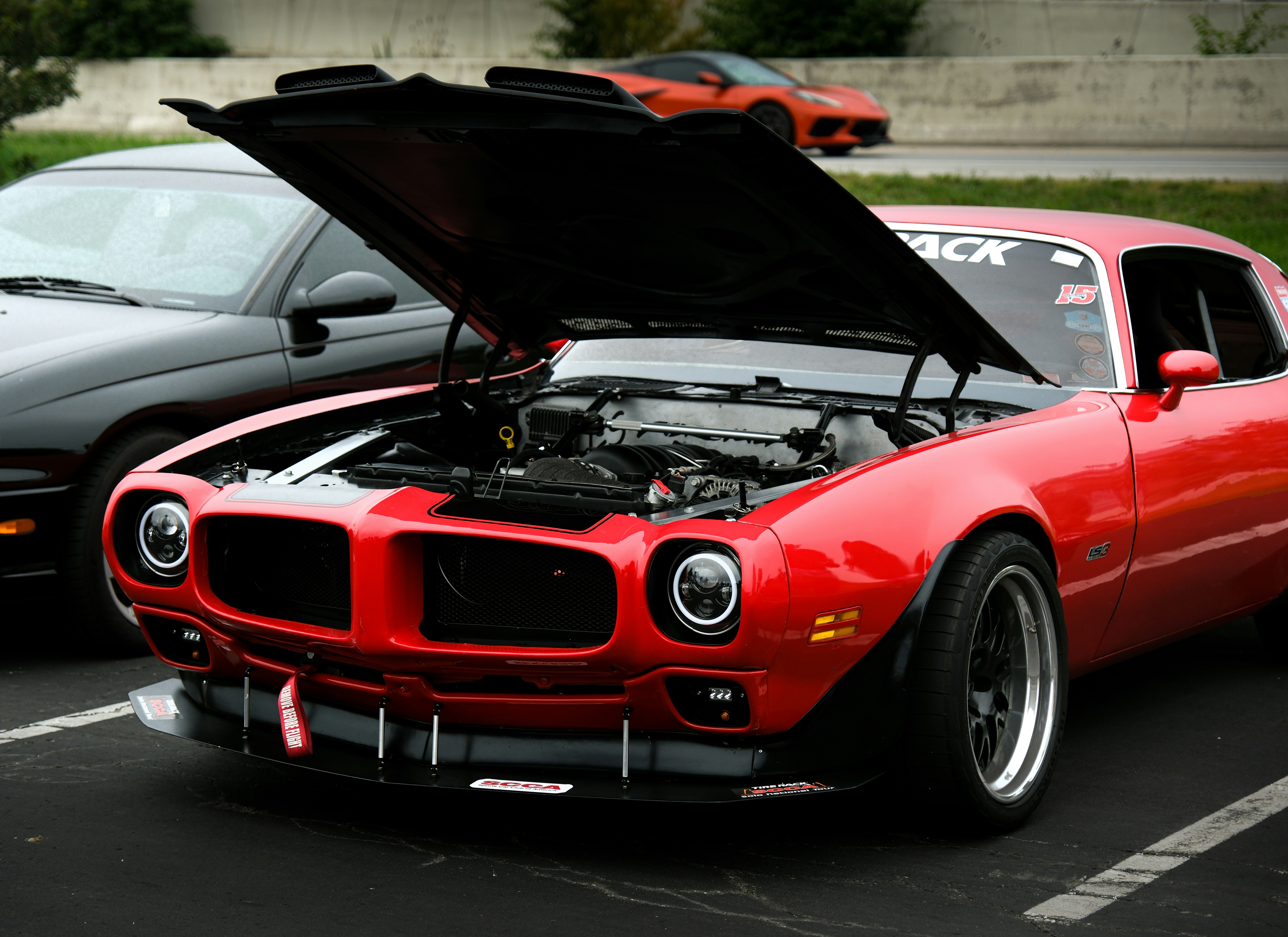 a red car with its hood open in a parking lot