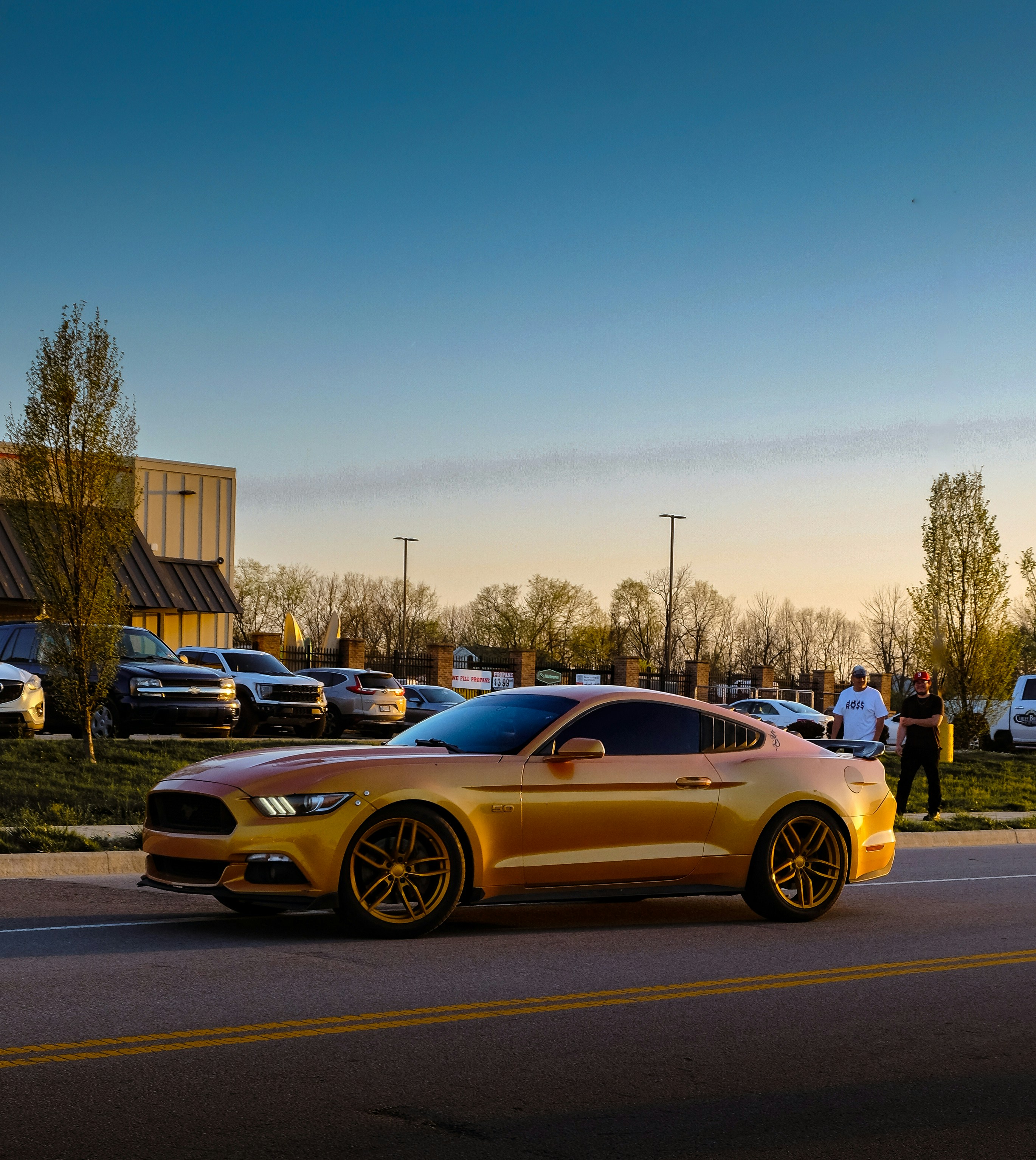 a gold mustang parked on the side of the road