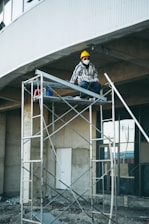 a man sitting on a scaffold in front of a building