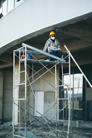 a man sitting on a scaffold in front of a building