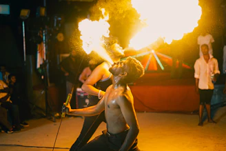 a shirtless man holding a fire stick in front of a crowd