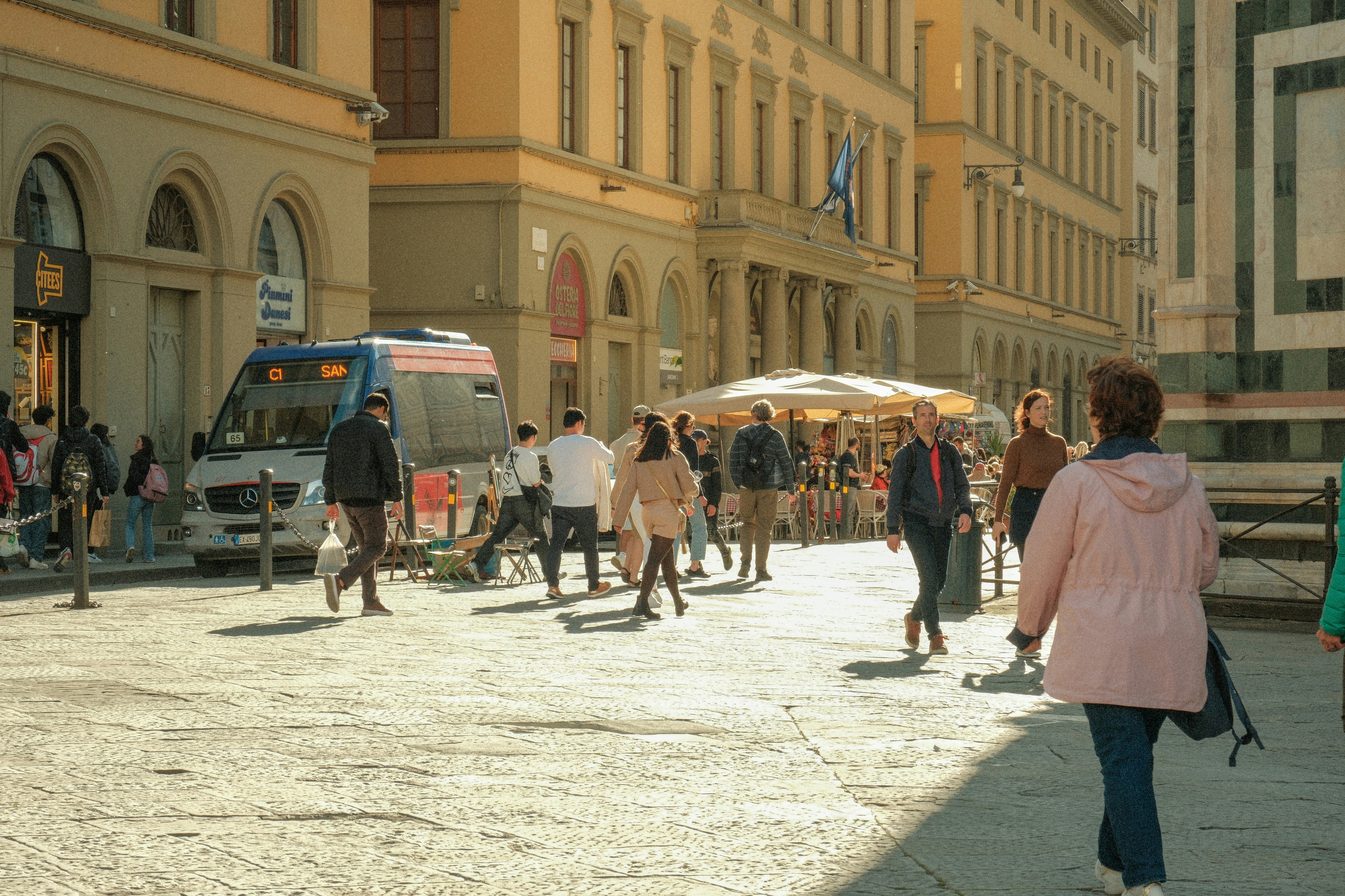 un gruppo di persone che camminano lungo una strada accanto a edifici alti