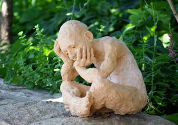 a statue of a man sitting on top of a rock