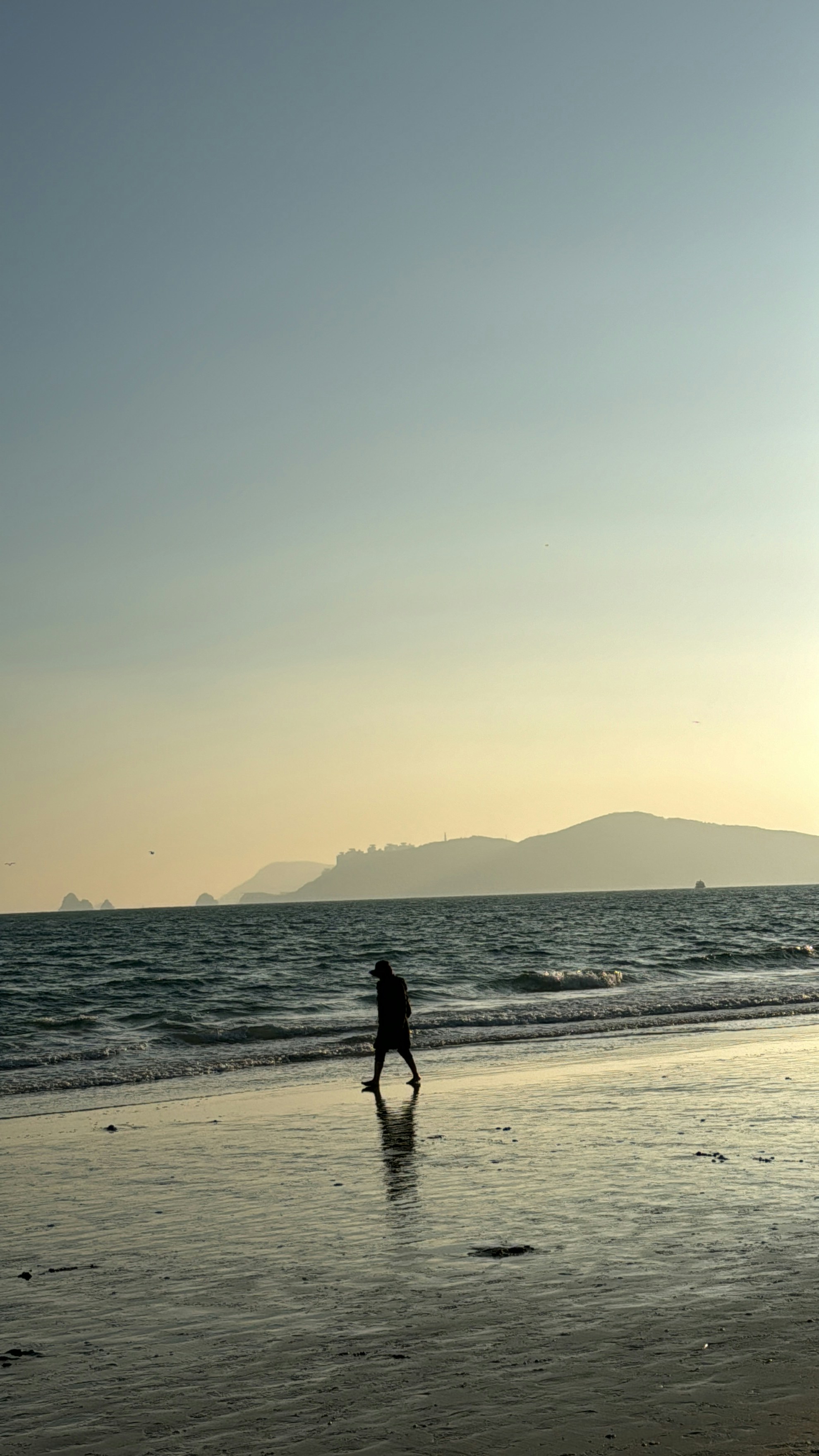 a person walking on a beach near the ocean